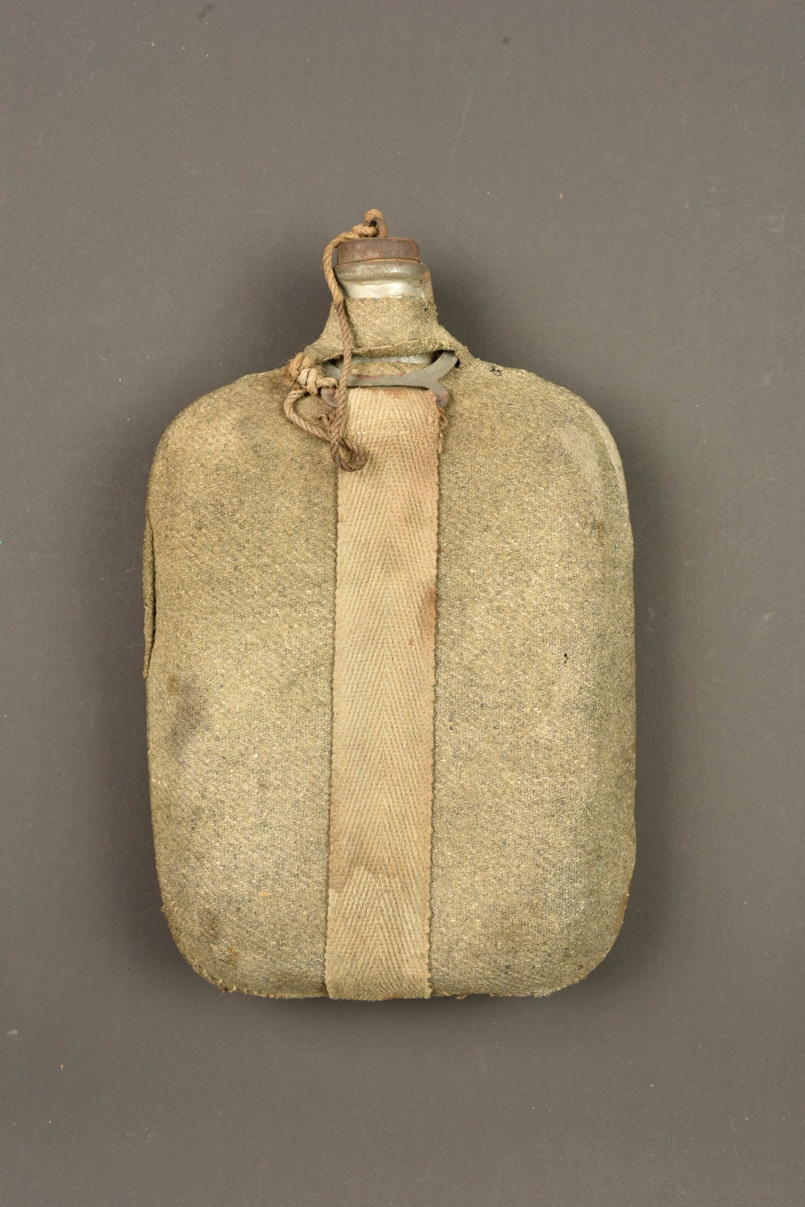 Bidon italien modele 1917. Italian Model 1917 canteen: Bidon italien modele 1917. Bidon en fer recouvert de drap grigio-verde, quelques petits trous, une dechirure sur un cote, avec sa sangle, son bouchon. Usure d usage, patine. Italian Model 1917 canteen
