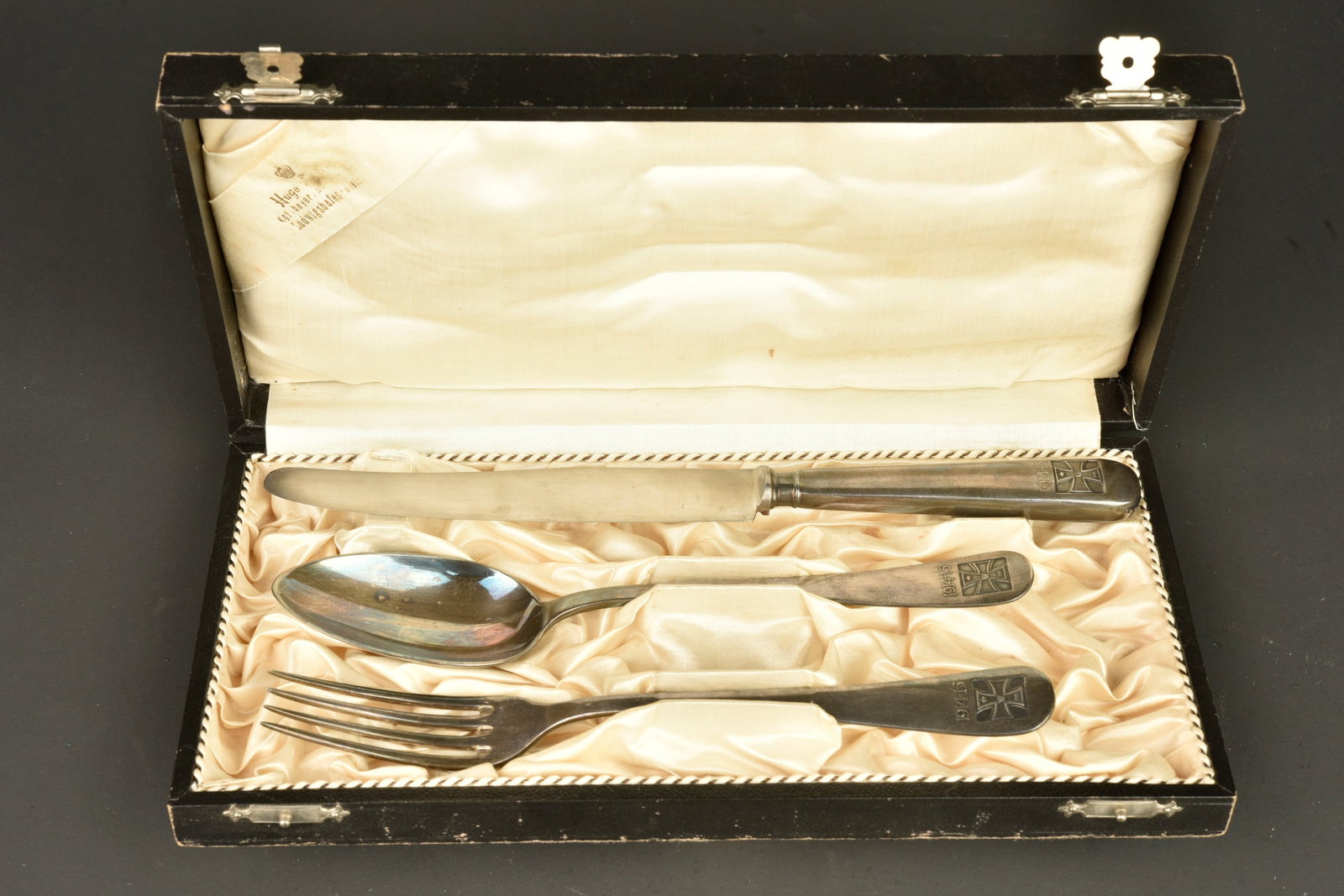 Couverts en metal argente a motif de croix de fer dans leur coffret. Silver plated cutlery with Iron: Couverts en metal argente a motif de croix de fer dans leur coffret. Coffret de 3 couverts Couteau, fourchette et cuillere, en metal argente, poincon B avec locomotive pour joailler Bruckmann, poincon