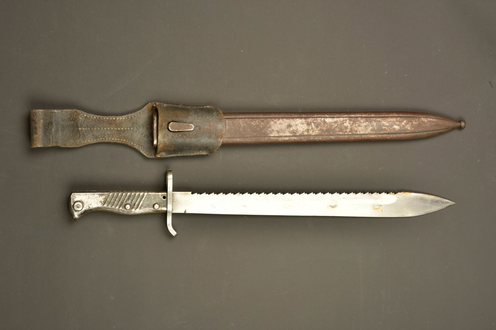 Baionnette allemande ersatz a dents de scie. German ersatz sawback bayonet: Baionnette allemande ersatz a dents de scie. Baionnette ersatz EB42. Belle lame a dents de scie, poignee metallique, bouton ressort fonctionnel. Avec son fourreau specifique en metal rainure. Porte fo