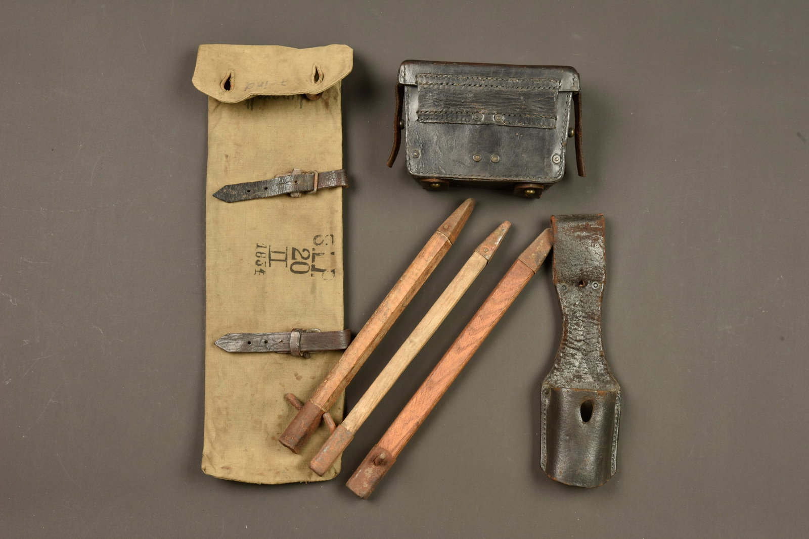 Lot d equipements allemands. Lot of German equipment: Lot d equipements allemands. Un etui a piquets de tente receptionne au KBA II, puis reutilise sans doute en Police et Jeunesses, nombreux marquages. Contient 3 sardines en bois et fer. Un porte baionn