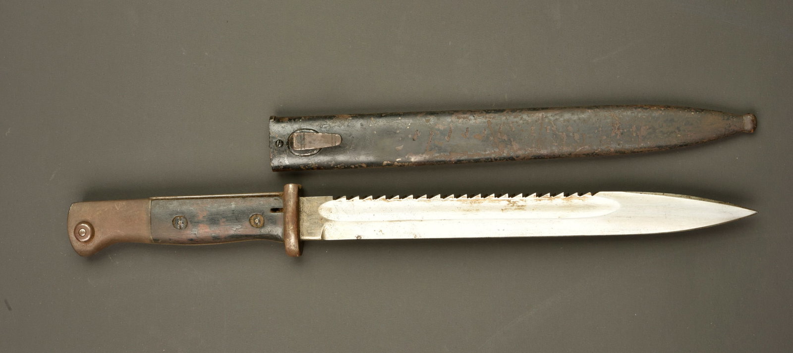 Baionnette 84-98 dents de scie. German 84/98 sawback bayonet: Baionnette 84-98 dents de scie. Lame du fabricant Gottlieb, poincon imperial au dos. Dents de scie. Poignee avec pare flamme, plaquettes bois, bouton ressort fonctionnel. Fourreau fer laque noir. Usur