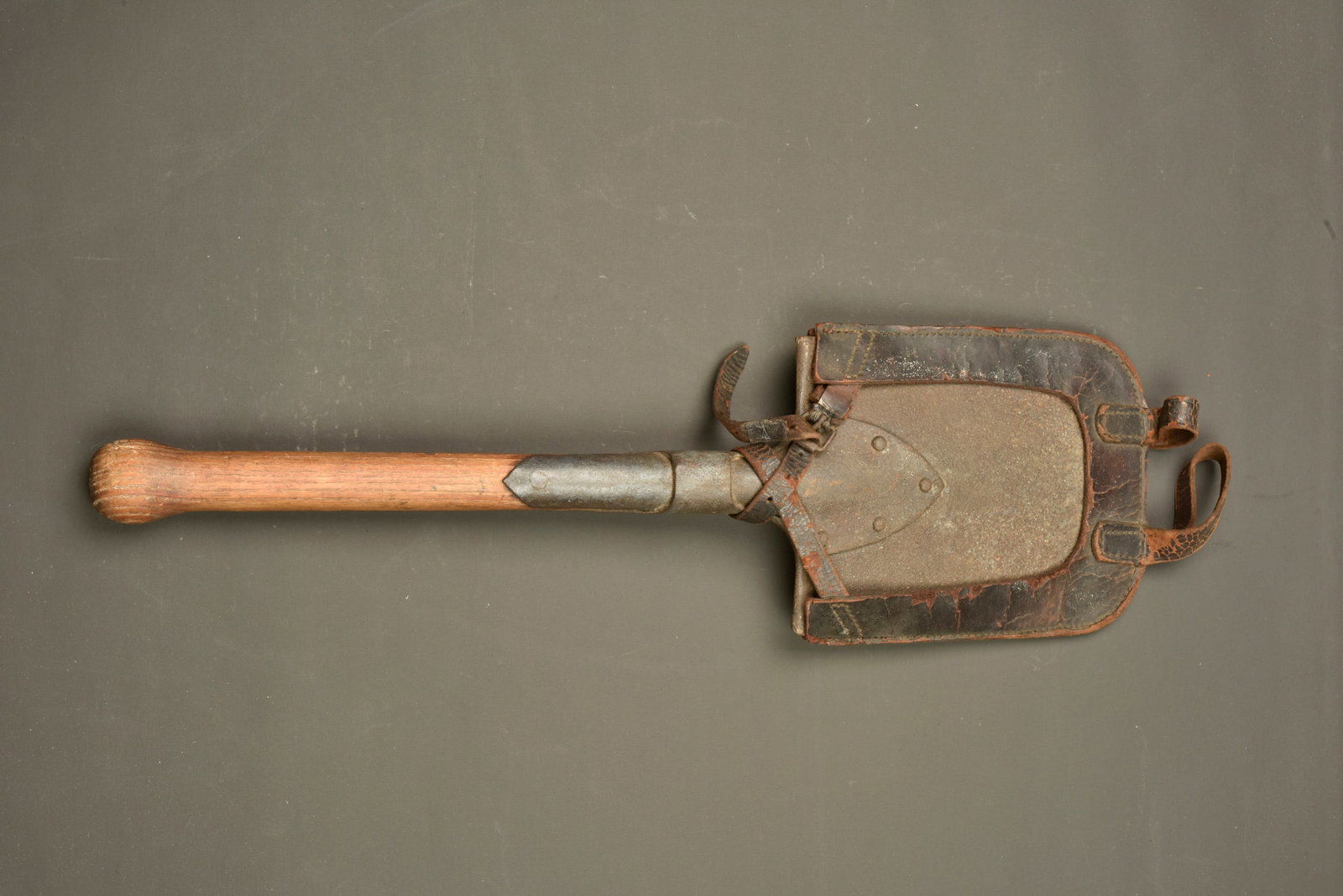 Pelle individuelle allemande avec porte pelle cuir. German entrenching tool with leather carrier: Pelle individuelle allemande avec porte pelle cuir. Pelle droite, oxydation. Etui en cuir, grenele d un cote, pas de marquage visible. Avec ses passants. La sangle de maintien a ete reparee et est fra
