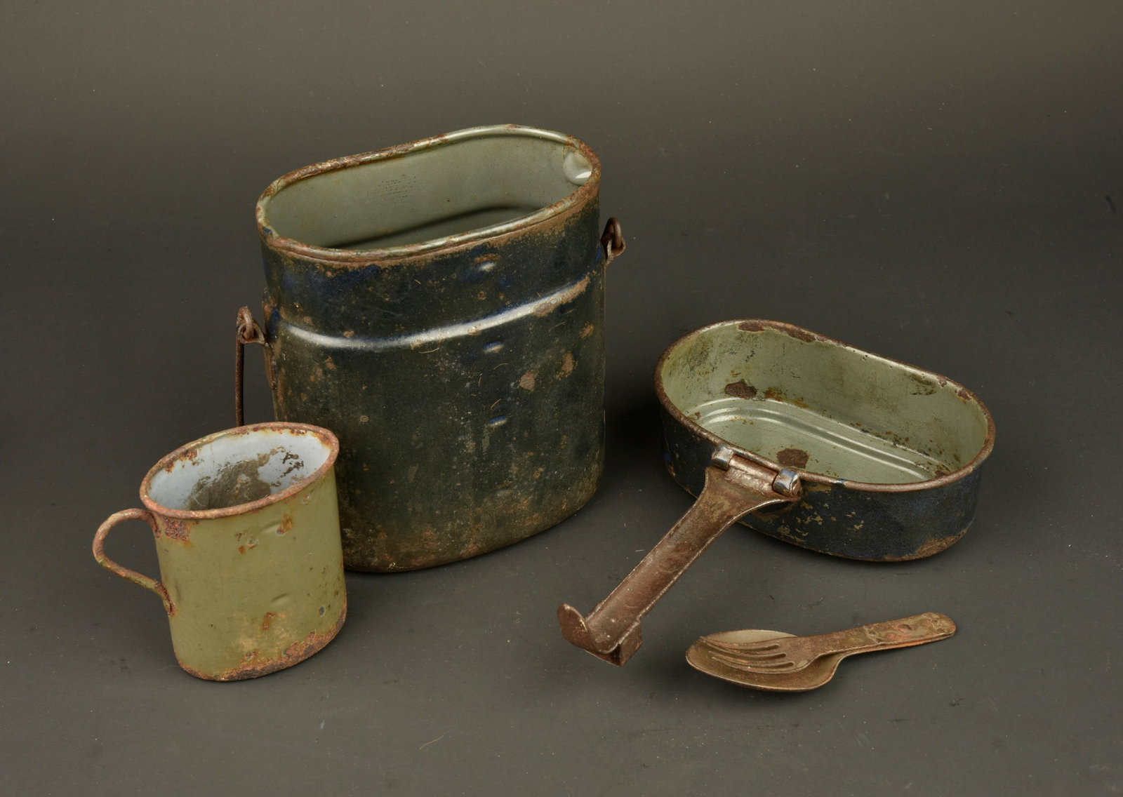 Gamelle, quart et couverts allemands. German mess tin, drinking cup and cutlery set: Gamelle, quart et couverts allemands. Gamelle emaillee foncee, bas marque fabricant Hanel. Quart emaille feldgrau fabricant Wupperman 1917, couverts combines en fer. Oxydation, usure d usage, patine. 