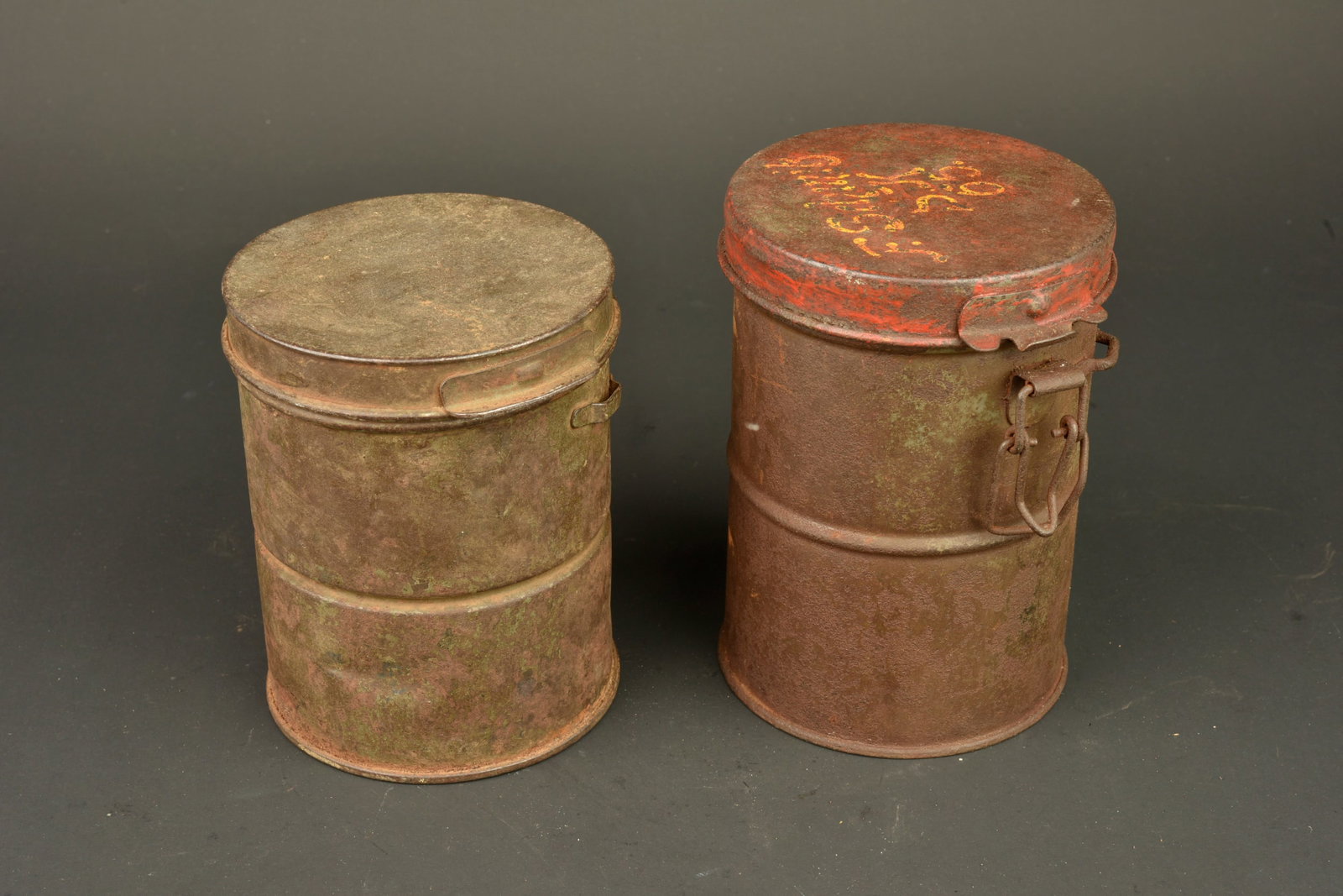 Lot de 2 boites de masque anti-gaz allemands. Lot of two German gas mask canisters: Lot de 2 boites de masque anti-gaz allemands. Une boite pour Gummimaske avec sa notice dans le couvercle. Oxydation. Une boite pour Lederschutzmaske, restes de peinture rouge sur le couvercle et inscr