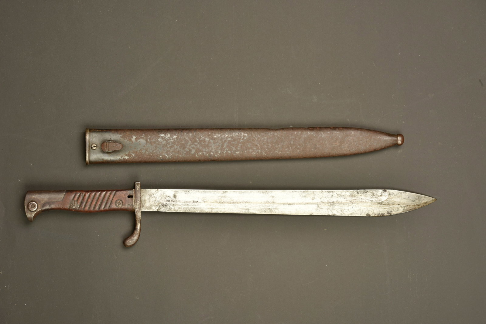 Baionnette allemande 98-05. German 98/05 bayonet: Baionnette allemande 98-05. Lame datee 1915 du fabricant C.G. HAENEL de Suhl, oxydation superficielle. Croisiere avec amorce de douille. Plaquettes bois striees. Bouton ressort fonctionnel. Fourreau f