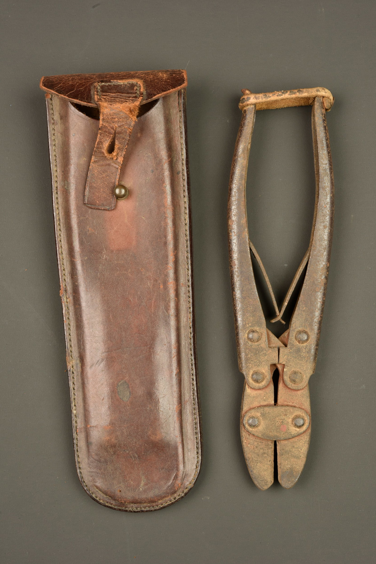 Pince coupante allemande M1911 dans son etui cuir. German Model 1911 wire cutters in leather carrier: Pince coupante allemande M1911 dans son etui cuir. Pince complete, avec ses lames ressort et son sanglon de maintien en cuir. Logo fabricant pres des lames. Metal legerement oxyde. Dans un bel etui en