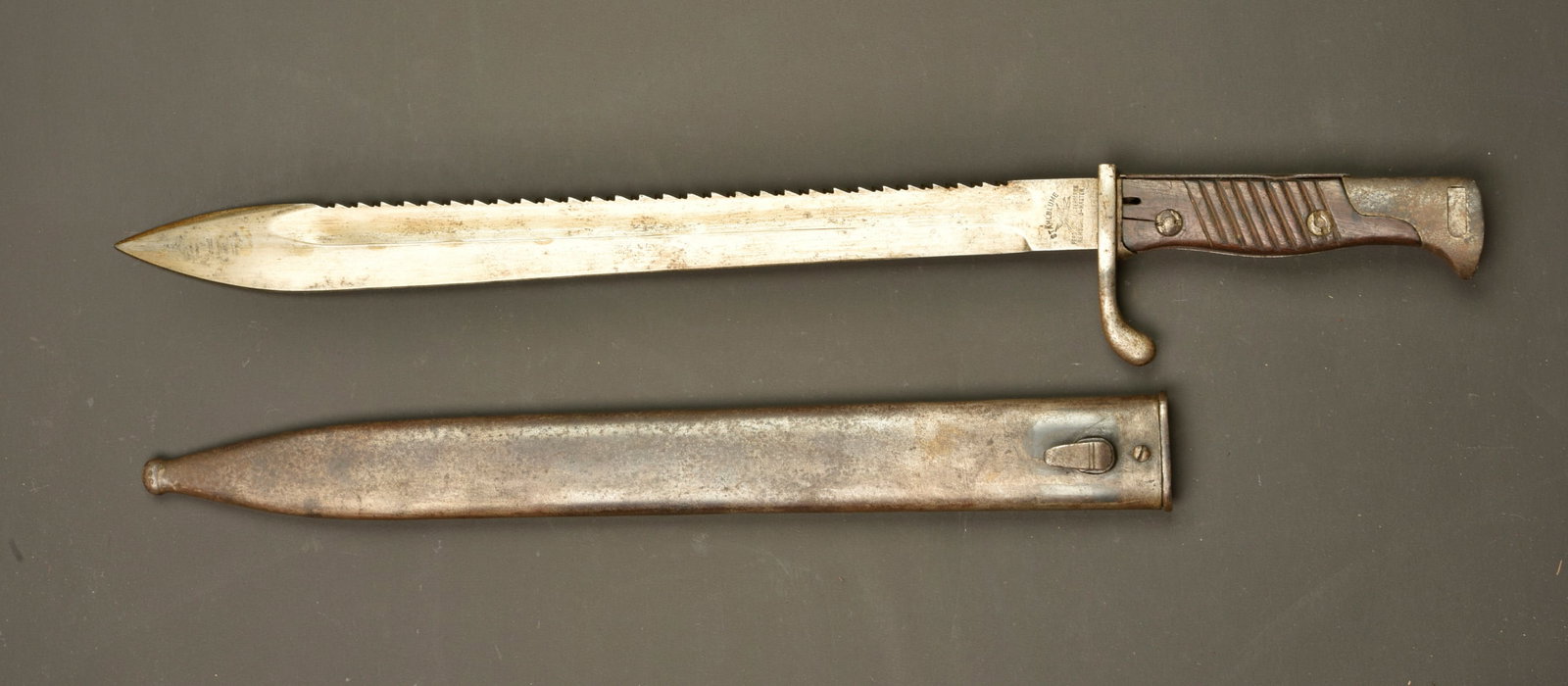 Baionnette allemande 98-05 dents de scie. German 98/05 sawback bayonet: Baionnette allemande 98-05 dents de scie. Lame datee 1916 du fabricant STAHLBLUME SCHLEUTERMANN de REMSCHEID-HASTEN, oxydation superficielle. Poignee avec pare flamme. Plaquettes bois striees. Bouton 