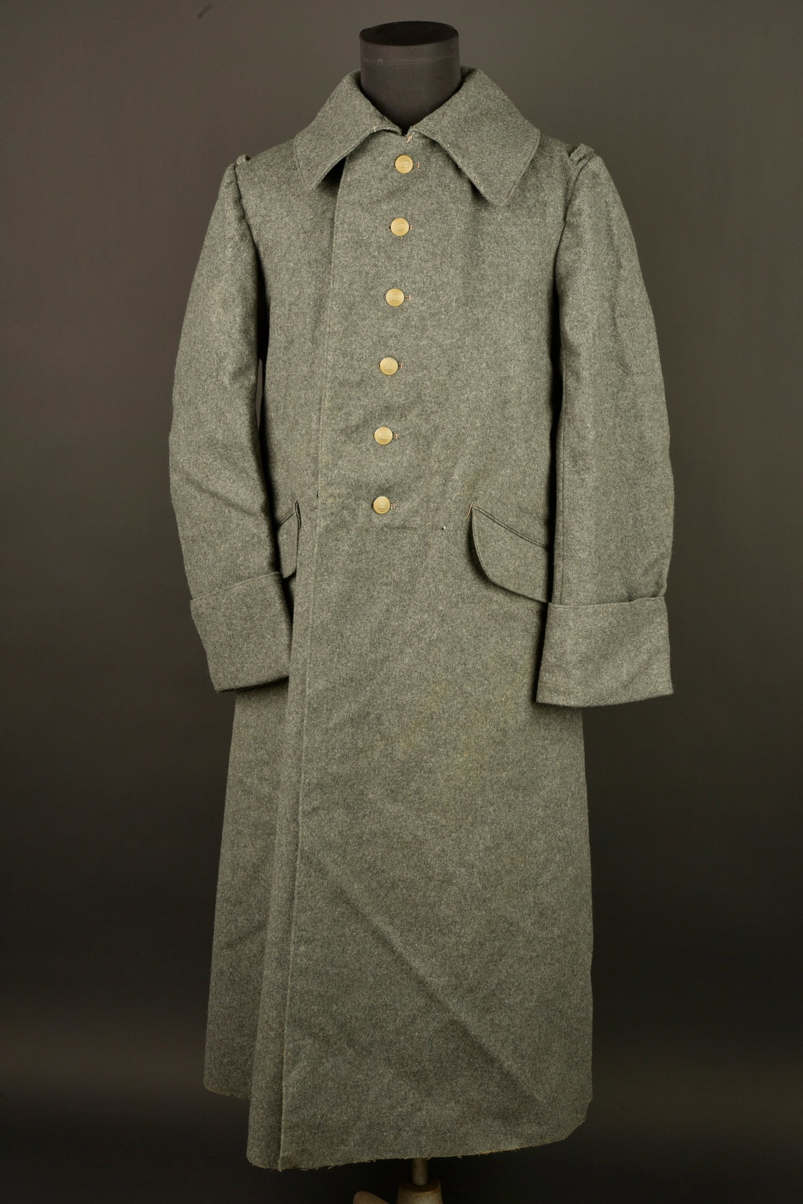Capote allemande feldgrau M1915 d un artilleur bavarois. German feldgrau Model 1915 greatcoat of a: Capote allemande feldgrau M1915 d un artilleur bavarois. En drap feldgrau, dans sa longueur, fermant par 6 boutons a la couronne, peints en feldgrau. Col en drap de fond, tel qu en dotation dans l arm