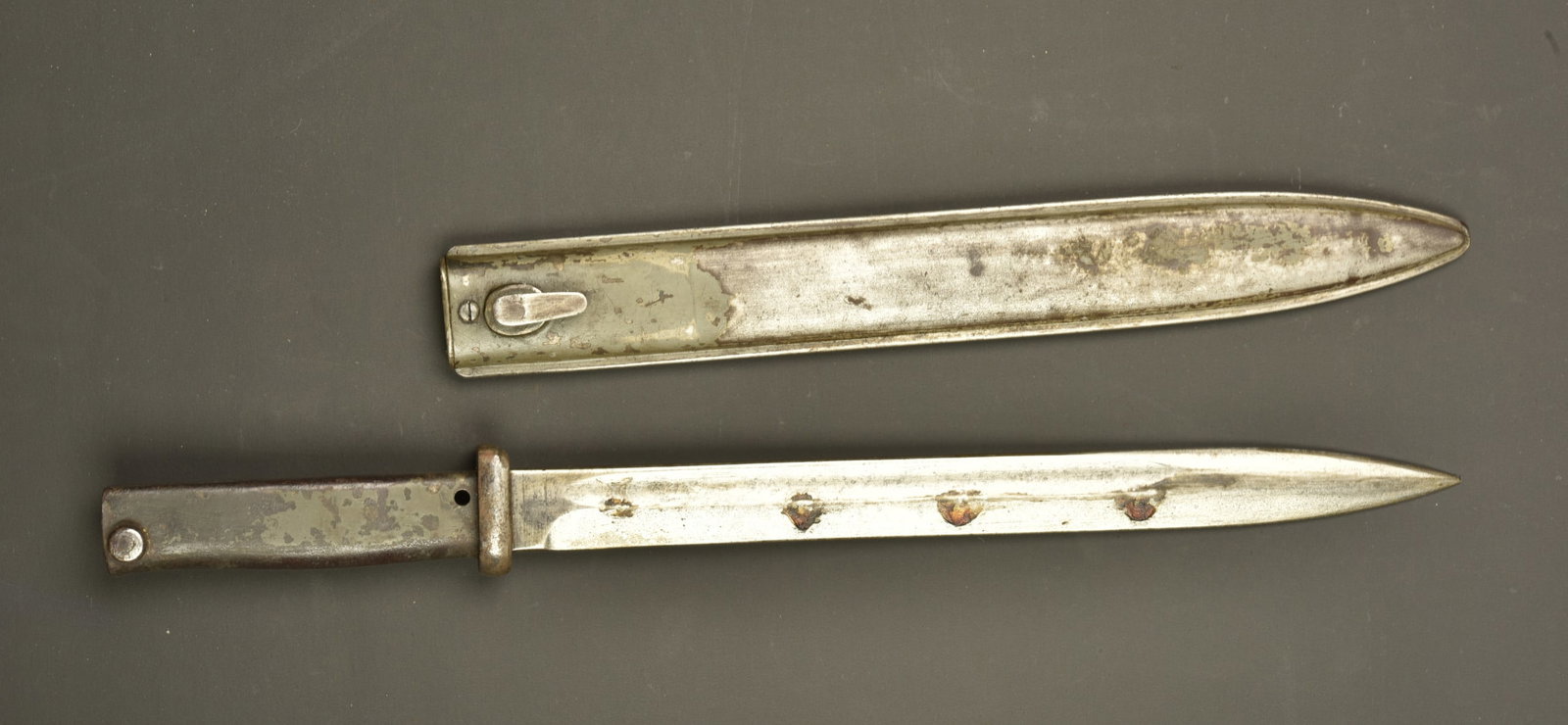 Baionnette ersatz. Ersatz bayonet.: Baionnette ersatz. Lame a pan creux. Poignee metal avec encore une partie de sa peinture feldgrau. Bouton ressort mobile mais dur. Fourreau fer FAG avec restes de peinture feldgrau. Usure d usage, pat