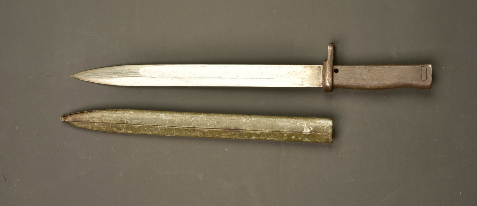 Baionnette ersatz. Ersatz bayonet.: Baionnette ersatz. Lame a pan creux. Poignee metal avec encore une partie de sa peinture feldgrau. Bouton ressort fonctionnel. Fourreau fer avec peinture feldgrau, fendu a son extremite. Usure d usage