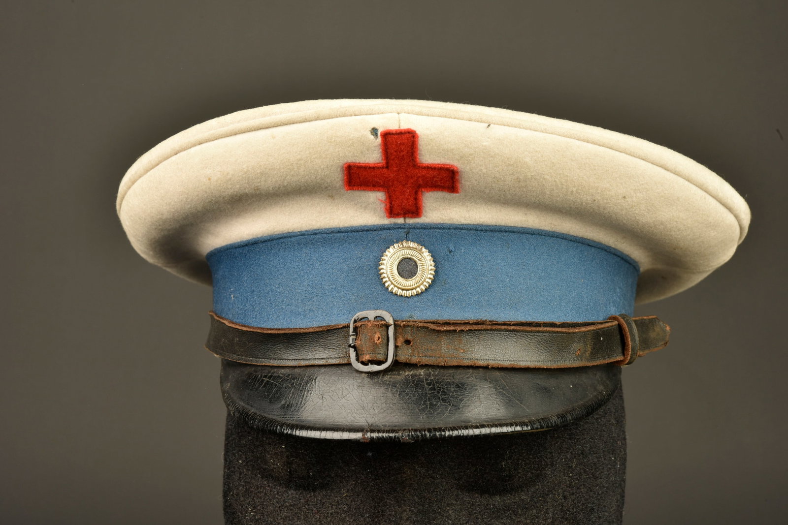 Casquette de sous-officier Sanitaire bavarois. Bavarian medical NCO visor cap.: Casquette de sous-officier Sanitaire bavarois. Calotte blanche avec croix rouge cousue. Bandeau bleu avec cocarde de sous-officier bavarois. Jugulaire en cuir. Visiere courte, noire, dessous lie de vi