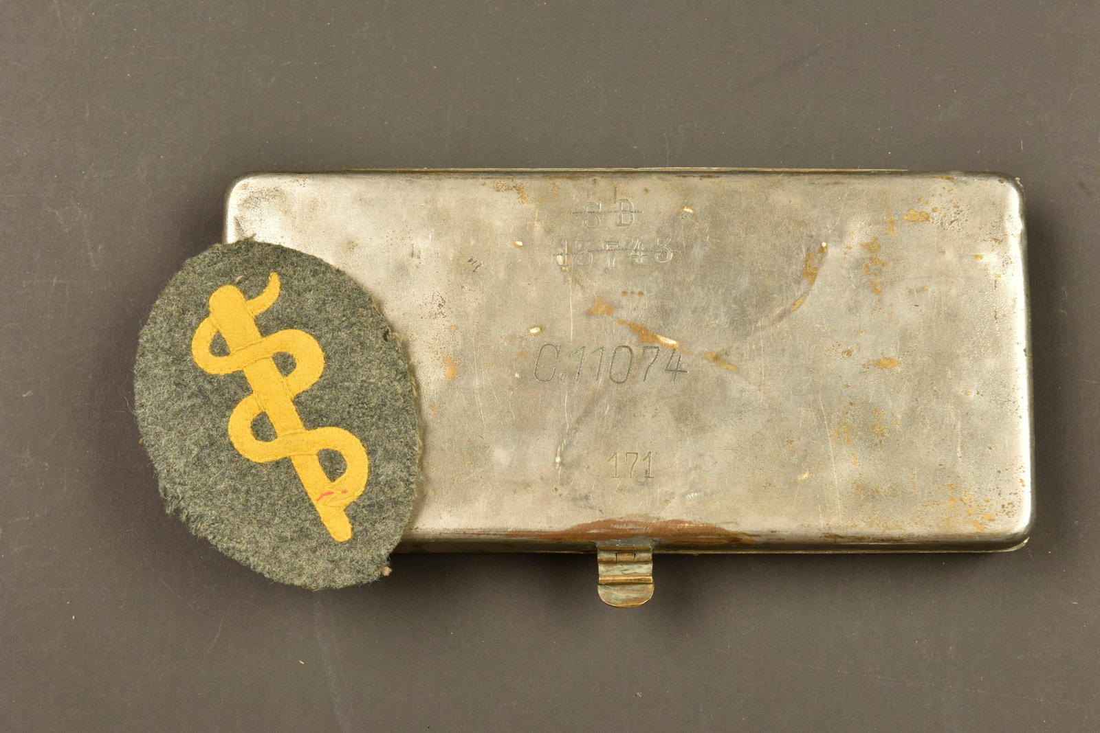 Insigne d infirmier allemand et boite d ustensiles medicaux. German medic badge and medical: Insigne d infirmier allemand et boite d ustensiles medicaux. Un bel insigne d infirmier allemand, en drap feldgrau avec serpent et baton d Esculape et serpent en drap jaune. Une boite d instrument chi