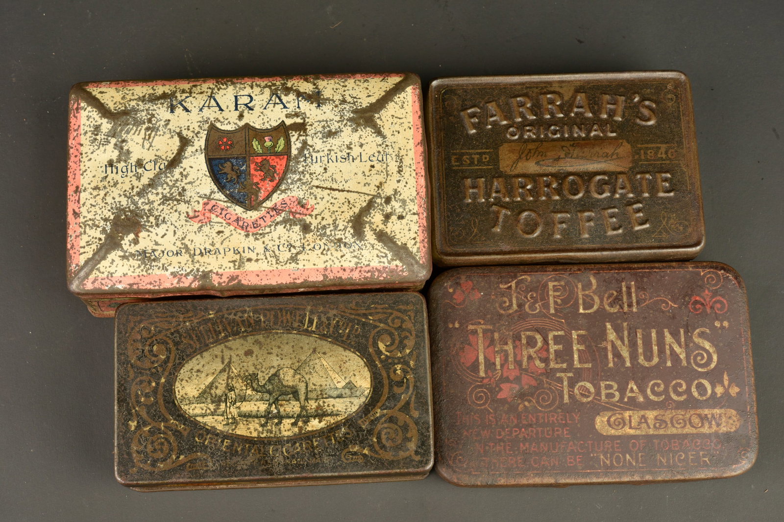 Lot de 6 boites anglaises et un quart. Lot of 6 British tins and one mug: Lot de 6 boites anglaises et un quart. 6 boites en fer blanc serigraphiees de diverses epoques pour tabac, cigarettes, bonbons. Marques Navy Cut, Karam, three nuns,...Un quart emaille marron. Oxydatio