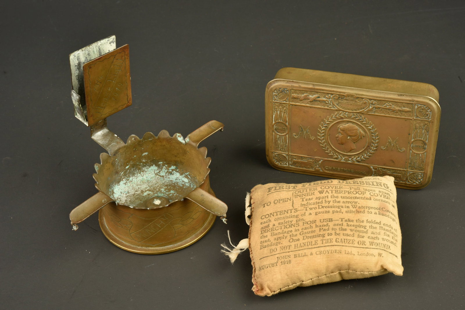 Lot de petits objets anglais. Lot of small British personal items: Lot de petits objets anglais. Un pansement date 1916, une boite Princess Mary Christmas 1914 vide et un cendrier porte allumette artisanal, realise dans une douille allemande, portant des noms de bata