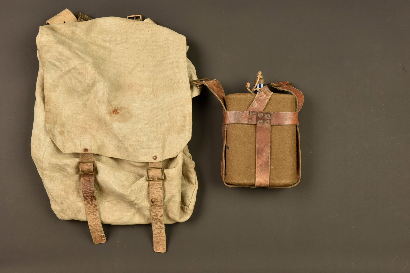 Sac a dos et bidon australiens pattern 1915. Australian Pattern 1915 backpack and canteen: Sac a dos et bidon australiens pattern 1915. Large pack australien en toile et cuir, tampon avec broad arrow. Usure d usage, quelques taches. Un bidon emaille bleu avec sa housse en feutrine, possible