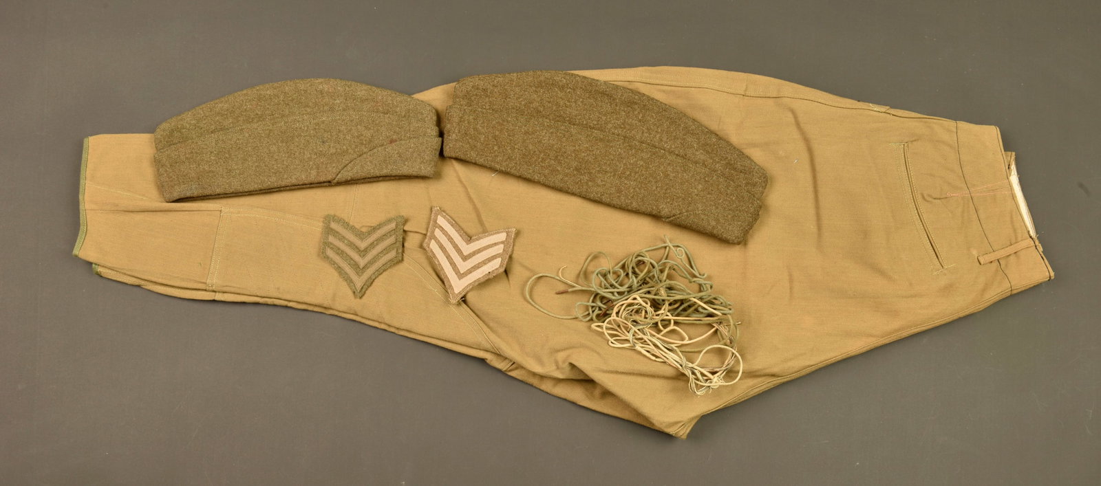 Culotte US en toile, bonnets de police et chevrons. US canvas breeches, overseas caps and chevrons: Culotte US en toile, bonnets de police et chevrons. Culotte en toile kaki avec renforts, en bel etat. Des lacets pour culotte ou guetres. 2 Bonnets de police en drap, periode a determiner, dont l un a