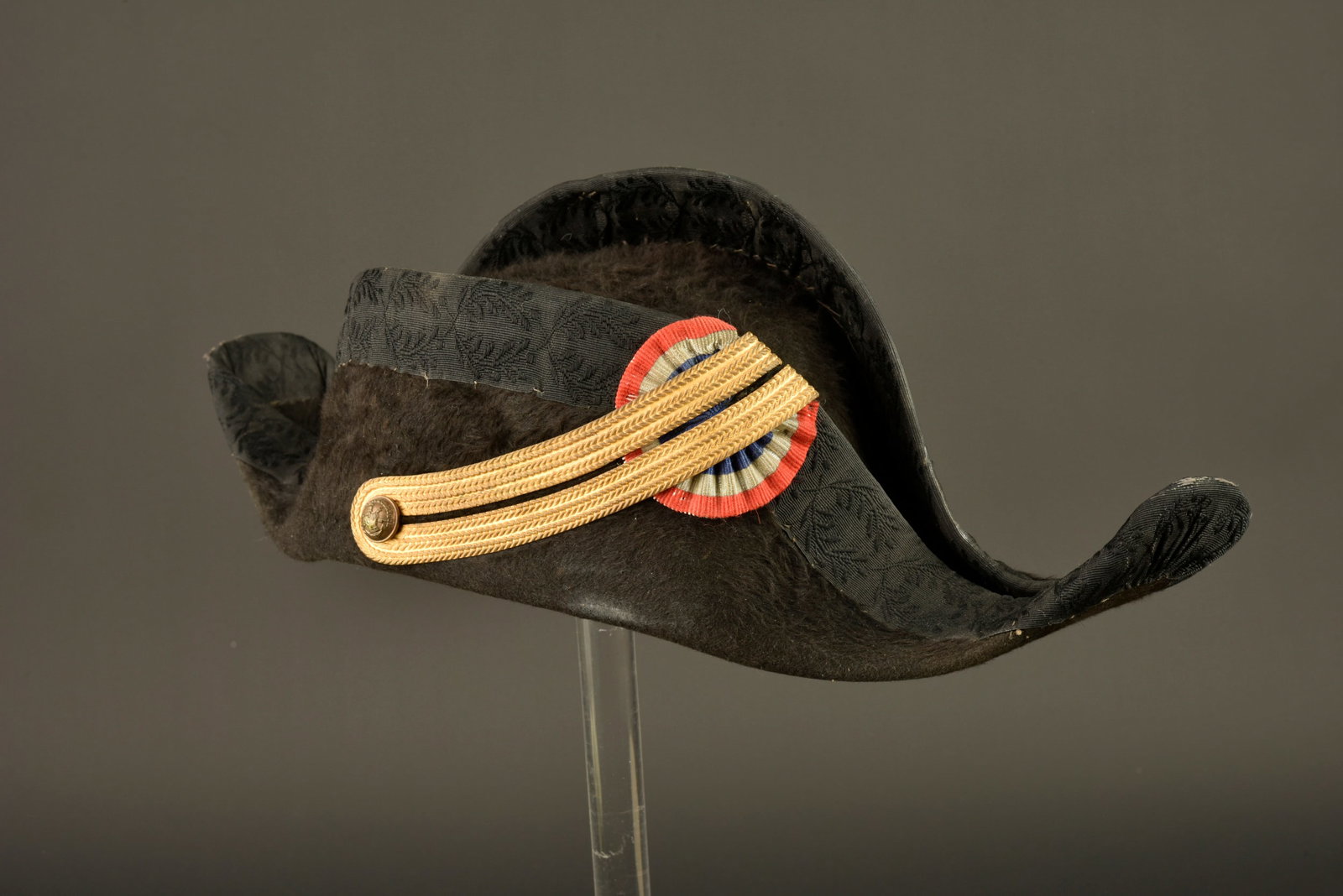 Bicorne de polytechnicien. Polytechnician bicorne: Bicorne de polytechnicien. Bicorne modele 1874 confectionne en feutre taupe noir, ganse en laiton retenant une cocarde tissee tricolore et maintenue par un bouton de l ecole polytechnique. Bandeau de 