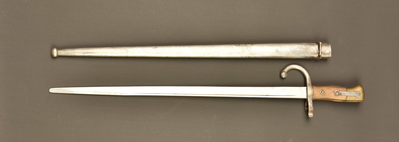 Baionnette 1874 scolaire. School bayonet model 1874.: Baionnette 1874 scolaire. Baionnette Gras dite scolaire, plaquettes en bois, bouton poussoir fonctionnel, lame arrondie a l extremite. Fourreau au modele. Model 1874 school bayonet. Gras-type training