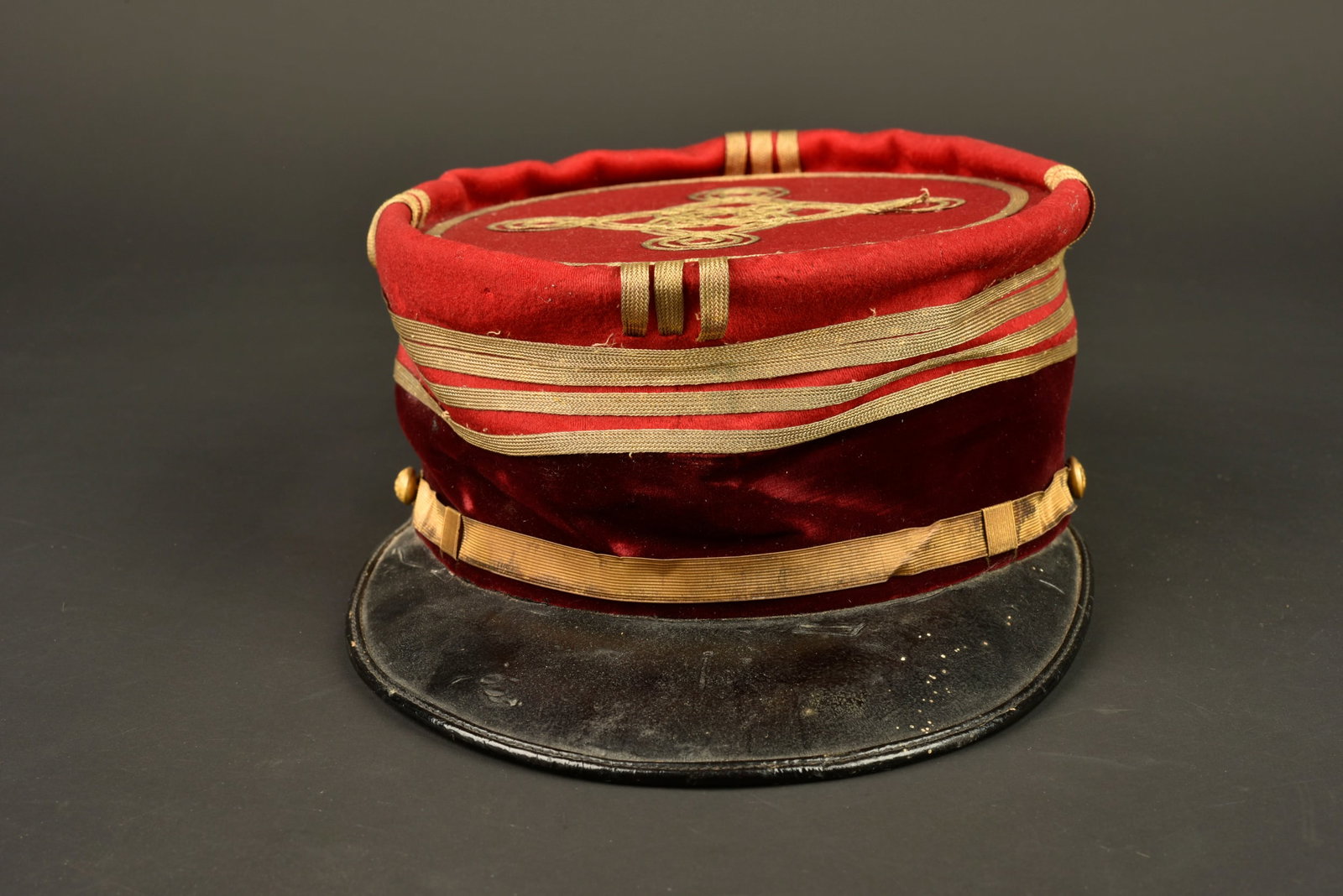 Kepi de commandant medecin. Commanding medical officer’s kepi.: Kepi de commandant medecin. Confectionne en drap garance, bandeau en velours cramoisi. Grades de sous commandant tisses a plat. Fausse jugulaire doree retenue par un bouton du service de sante et un d