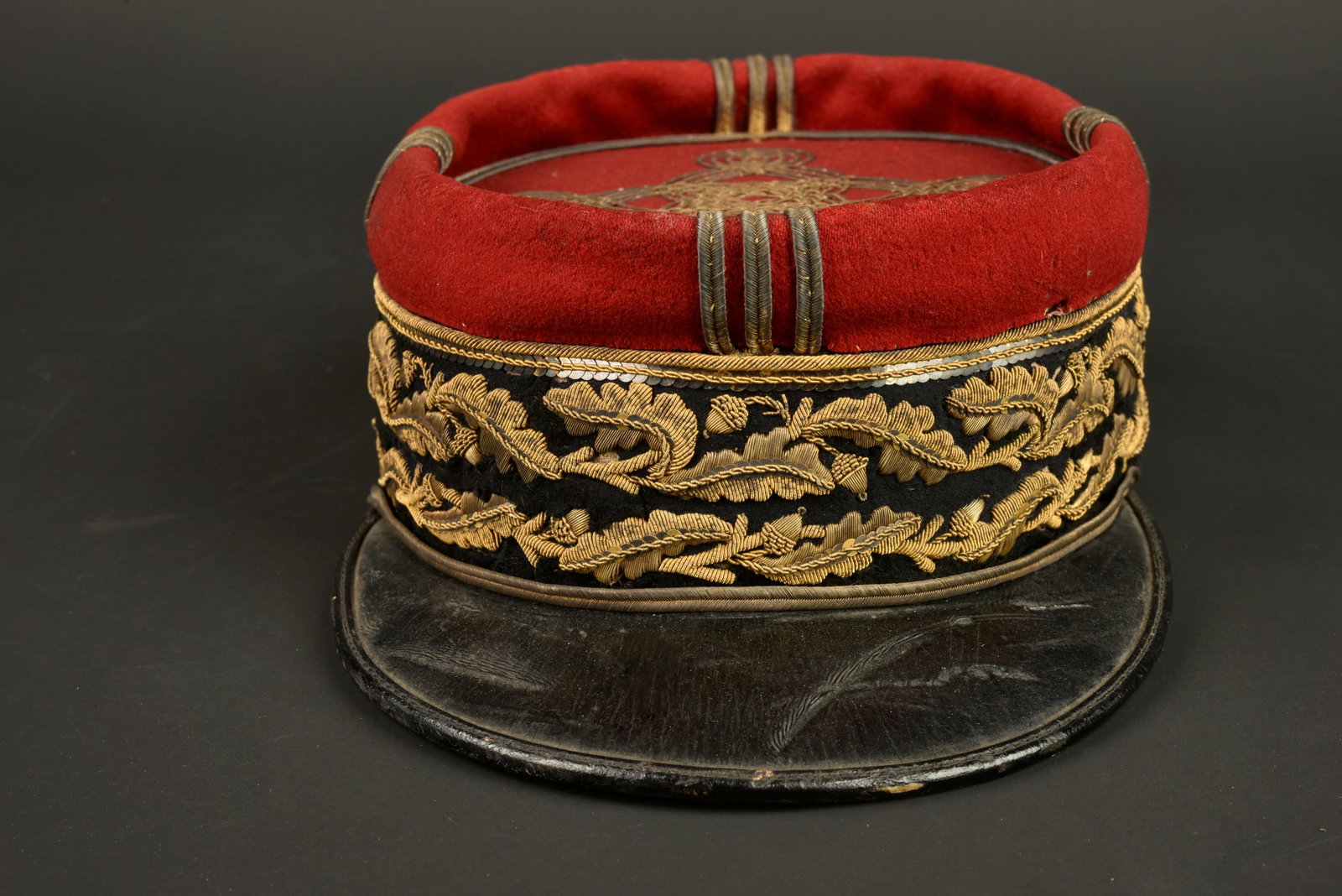 Kepi de general de division. Major general’s kepi.: Kepi de general de division. Kepi confectionne en drap garance et bandeau noir, rangee double de broderies en cannetille doree a feuilles de chene et a glands. Galons dores surmontant la broderie, fau