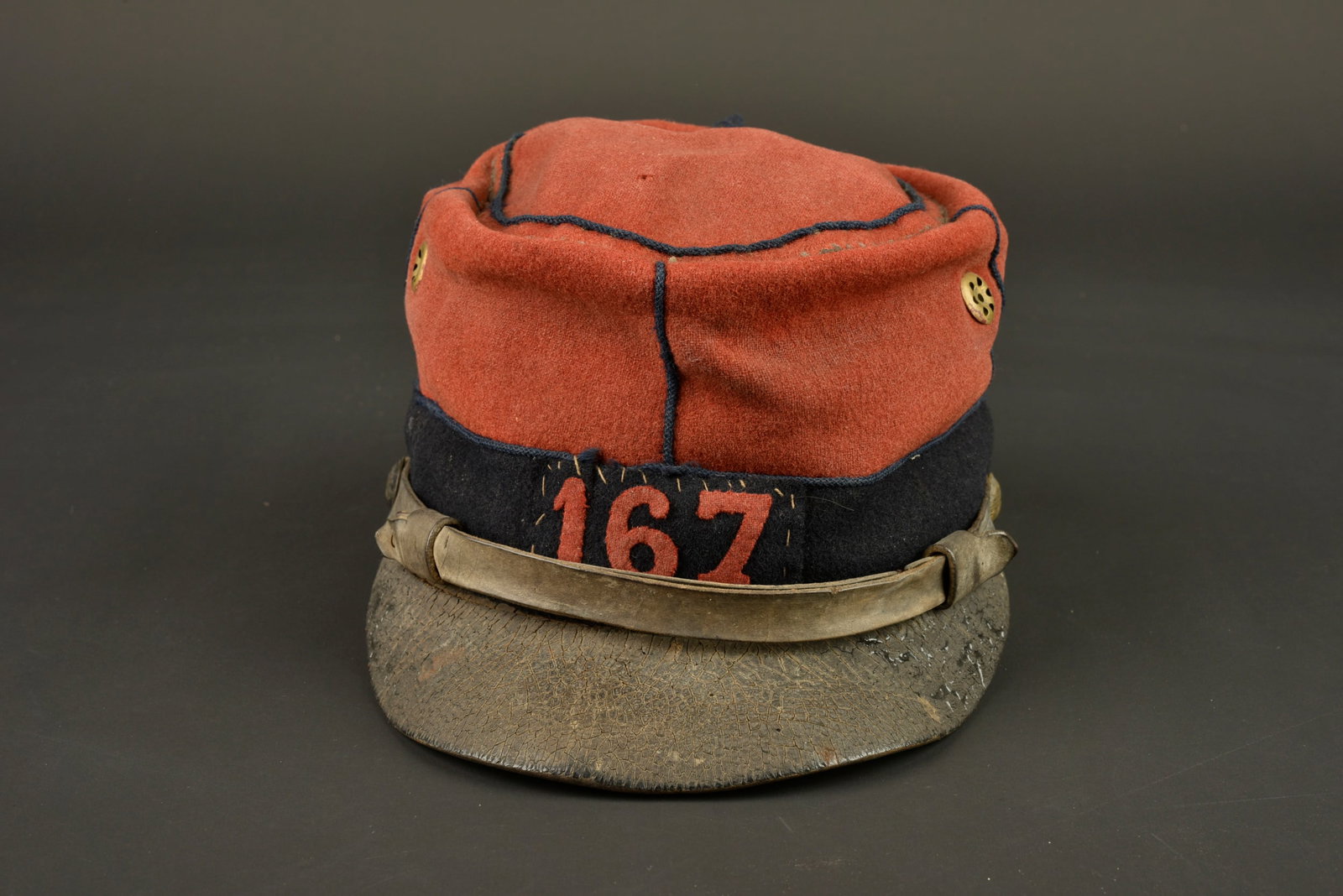 Kepi 1884 167eme de ligne. Kepi model 1884 of the 167th Line Regiment.: Kepi 1884 167eme de ligne. Confectionne en drap garance, bandeau en drap gris de fer bleute, aerateurs d origine presents depourvus de peinture. Chiffre 167 en drap garance cousu sur une piece de drap