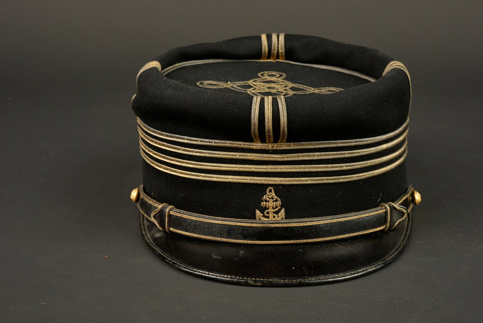 Kepi 1872 infanterie coloniale. Colonial infantry kepi, 1872 pattern.: Kepi 1872 infanterie coloniale. Realise en fin drap noir d officier, ancre coloniale brodee en cannetille. Fausse jugulaire doree recouverte par une fausse jugulaire en cuir laque surpiquee de fil dor