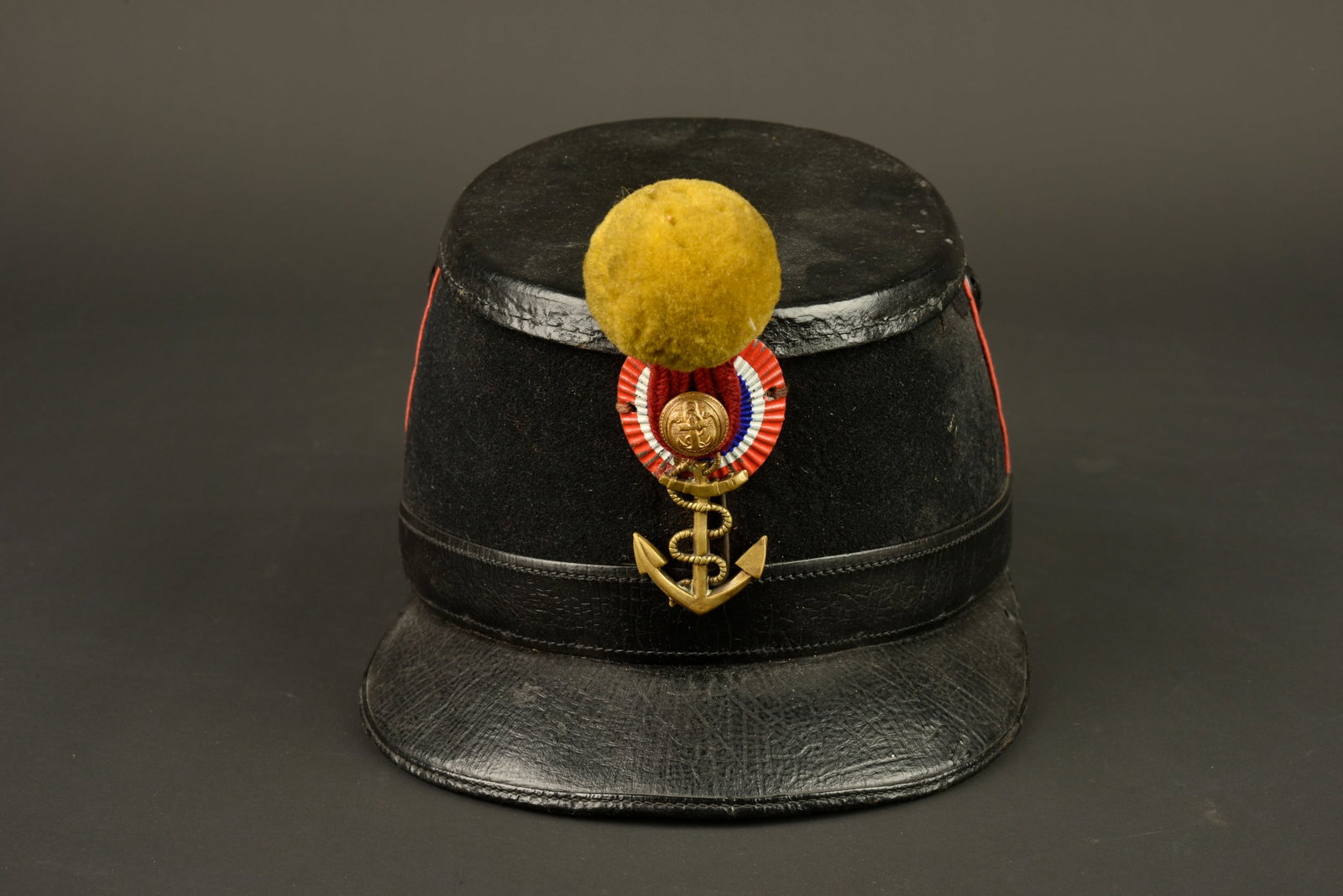 Shako 1872 infanterie coloniale. Colonial infantry shako, 1872 pattern.: Shako 1872 infanterie coloniale. Shako en carton recouvert d un fin drap noir, passepoil ecarlate. Bourdalou en cuir verni et calotte en cuir noir. Deux aerateurs en peinture d origine. A noter une pe