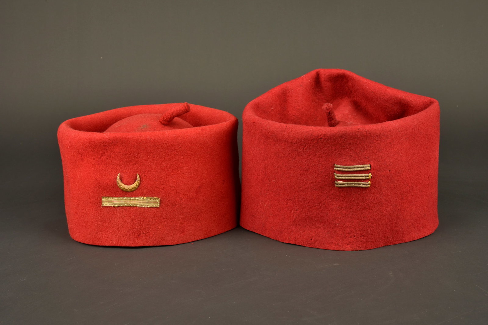 Ensemble de chechias. Set of chechias.: Ensemble de chechias. Comprenant une chechia modele 1879 confectionnee en tissu de laine feutree et cramoisi, a l avant se trouve un grade d adjudant surmonte d un croissant en metal rapporte. Chechia