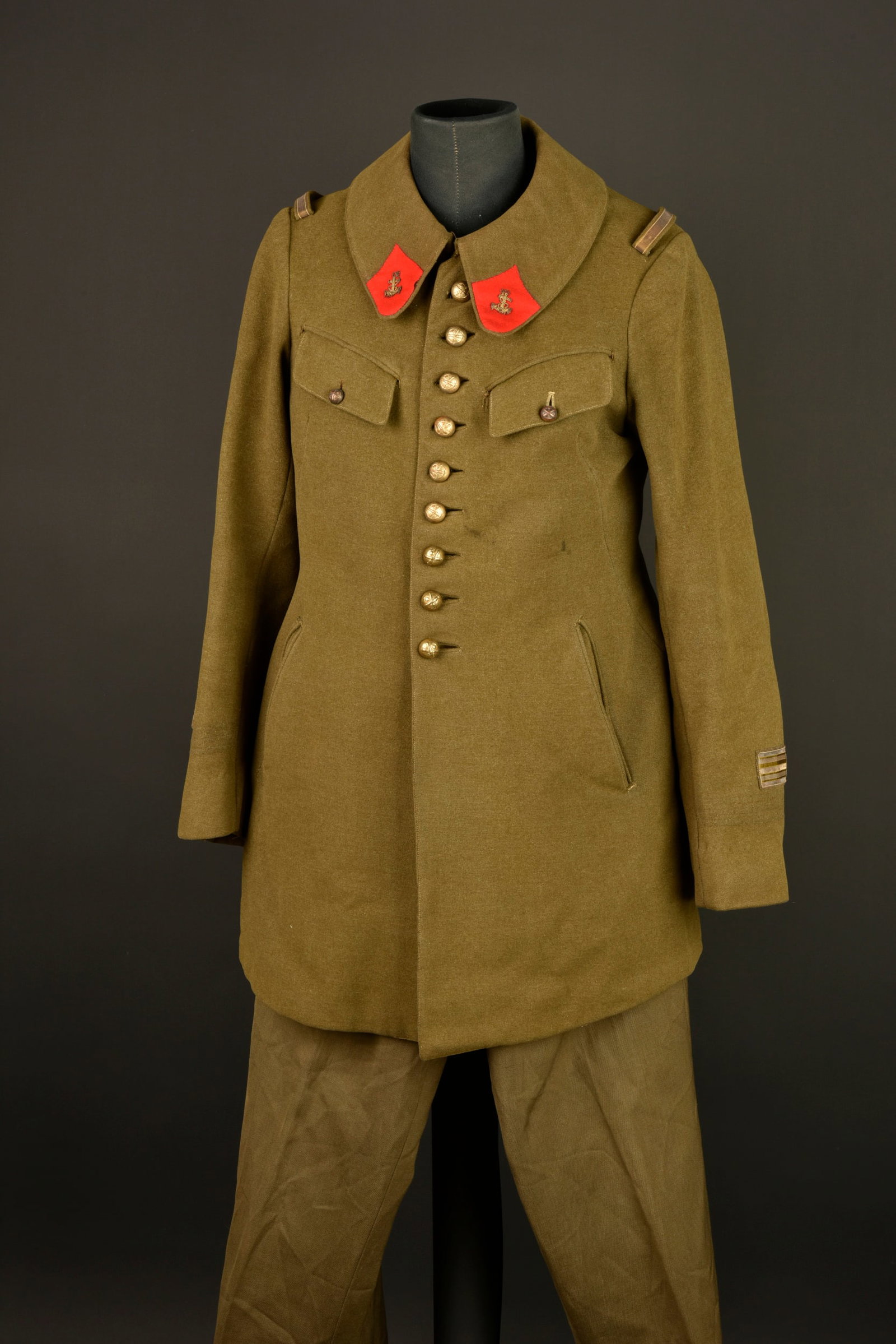 Ensemble artillerie coloniale. Colonial artillery grouping.: Ensemble artillerie coloniale. Comprenant un manteau d officier confectionne en fin drap kaki, pattes de col d officier de l artillerie coloniale avec ancre brodee cannetille. Deux poches de poitrine 