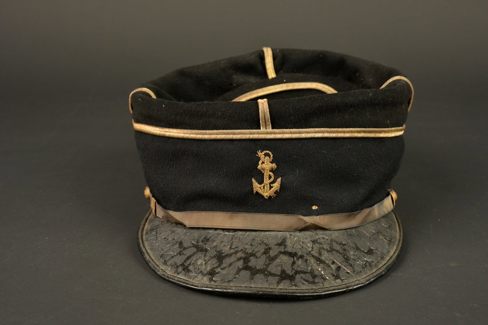 Kepi d adjudant infanterie coloniale. Colonial infantry adjutant’s kepi.: Kepi d adjudant infanterie coloniale. Fabrication tailleur confectionne en drap noir, galons cousus d origine, ancre brodee en cannetille. Fausse jugulaire plate et doree retenue par deux boutons de l