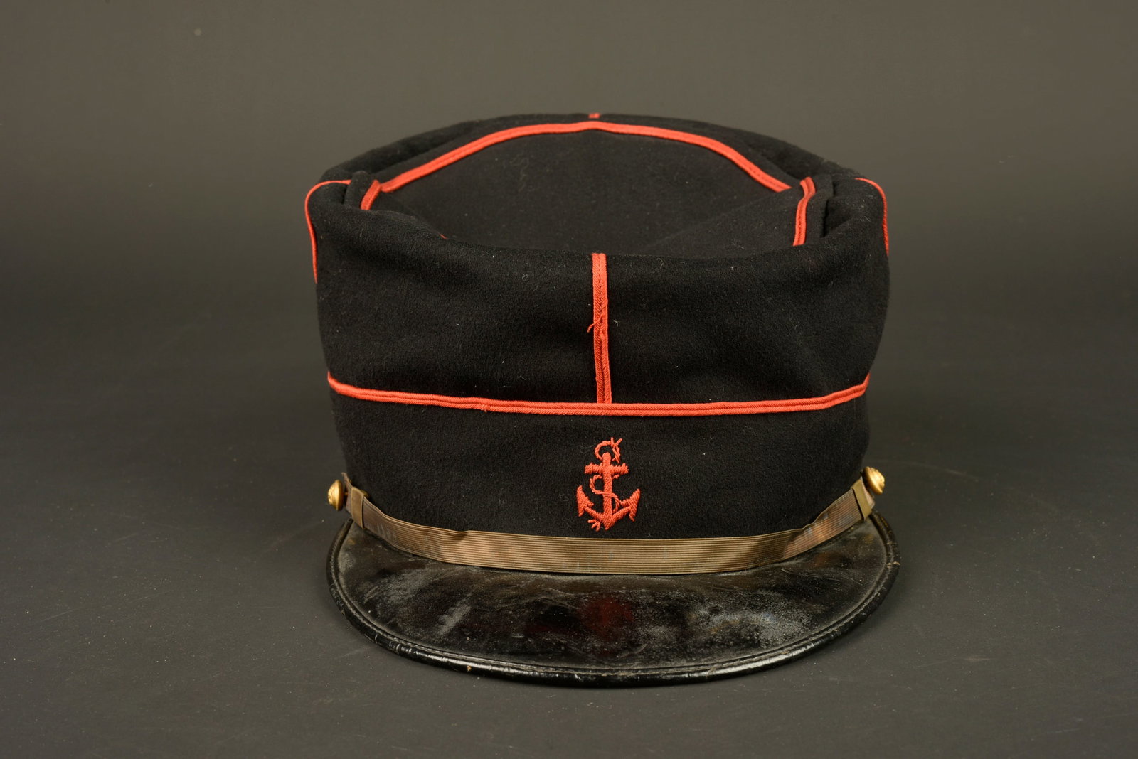 Kepi de marsouin. Marsouin (colonial infantryman) kepi.: Kepi de marsouin. Confectionne en drap de laine bleu fonce, passepoil ecarlate, ancre brodee au fil de coton ecarlate. Fausse jugulaire doree retenue par deux boutons de l infanterie coloniale. Visier