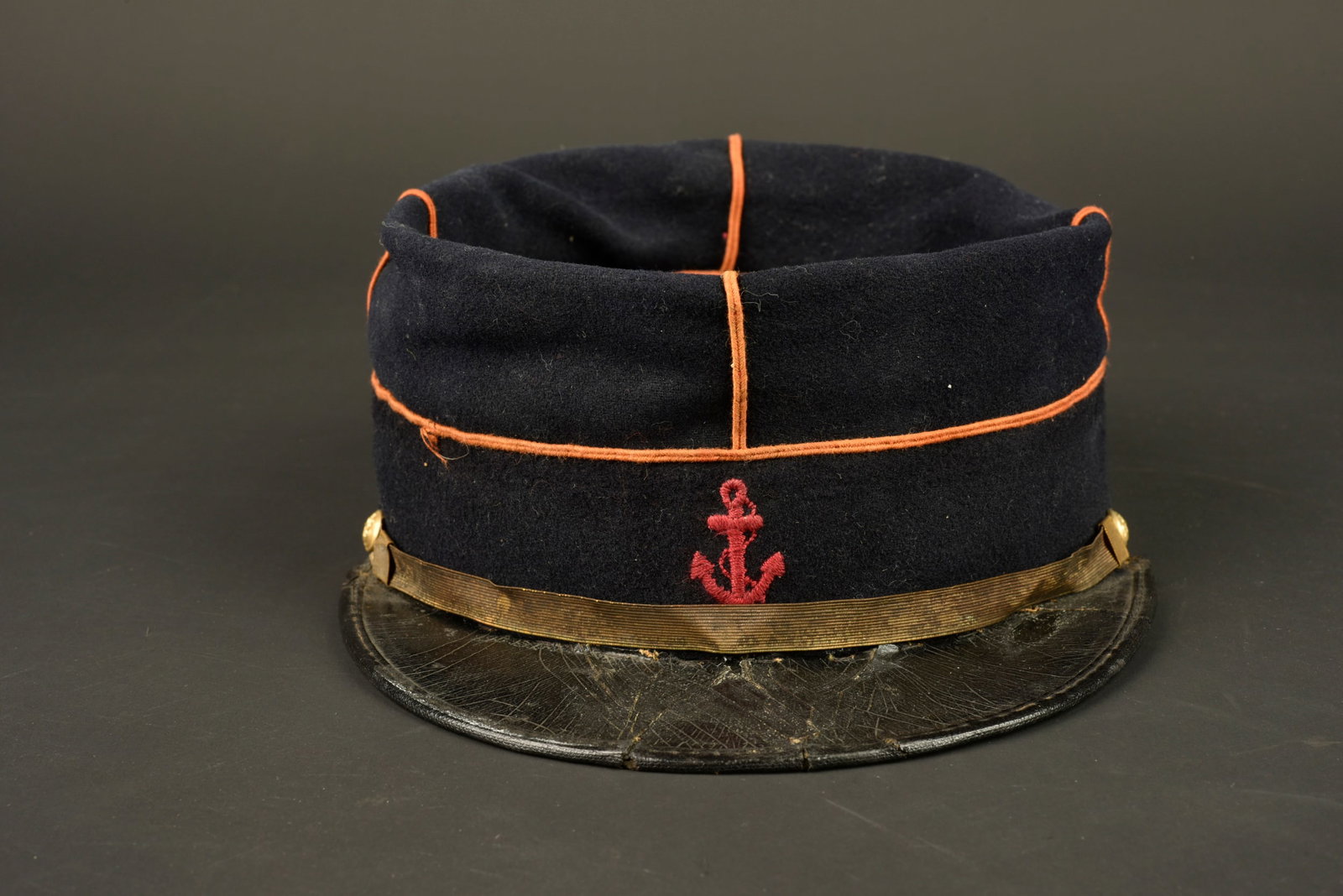 Kepi de marsouin. Marsouin kepi.: Kepi de marsouin. Confectionne en drap de laine bleu fonce, passepoil ecarlate decolore, ancre brodee au fil de coton ecarlate. Fausse jugulaire doree retenue par deux boutons de l infanterie colonial