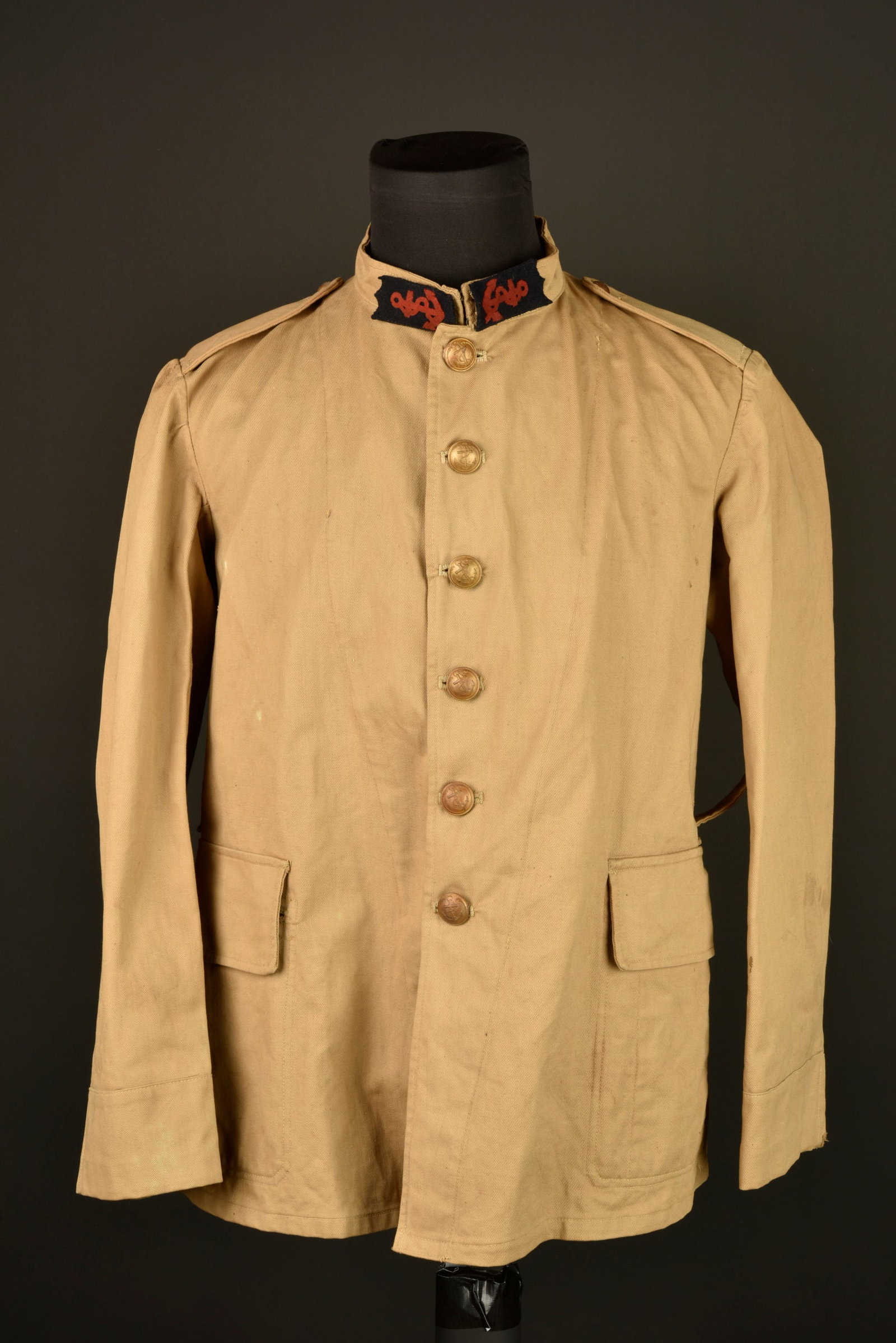 Vareuse infanterie coloniale. Colonial infantry service tunic.: Vareuse infanterie coloniale. Vareuse en toile confectionnee en tissu kaki clair et se fermant par six boutons aux armes de la coloniale. Deux poches a rabat, pattes d epaules montees d origine, patte