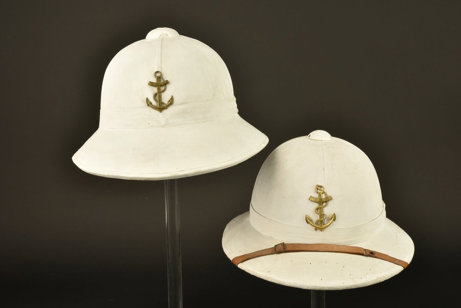 Casques coloniaux 1931. 1931 colonial helmets.: Casques coloniaux 1931. Comprenant un casque fabrique en liege et recouvert d une toile blanche recouvert de chaux, ancre en laiton montee d origine. Doublure en coton vert, coiffe et jugulaires
