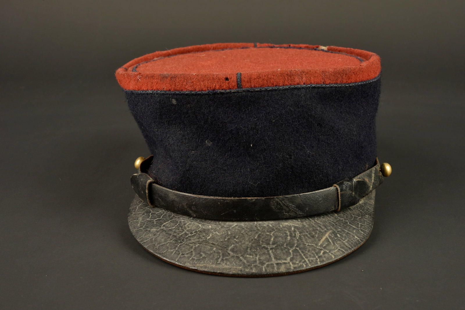 Kepi 1935 infanterie. 1935 Infantry kepi.: Kepi 1935 infanterie. Kepi modele 1935, plateau en drap garance, jugulaire en cuir du modele troupe retenue par deux petits boutons lisses dores. Visiere en cuir portant un cachet de controle,