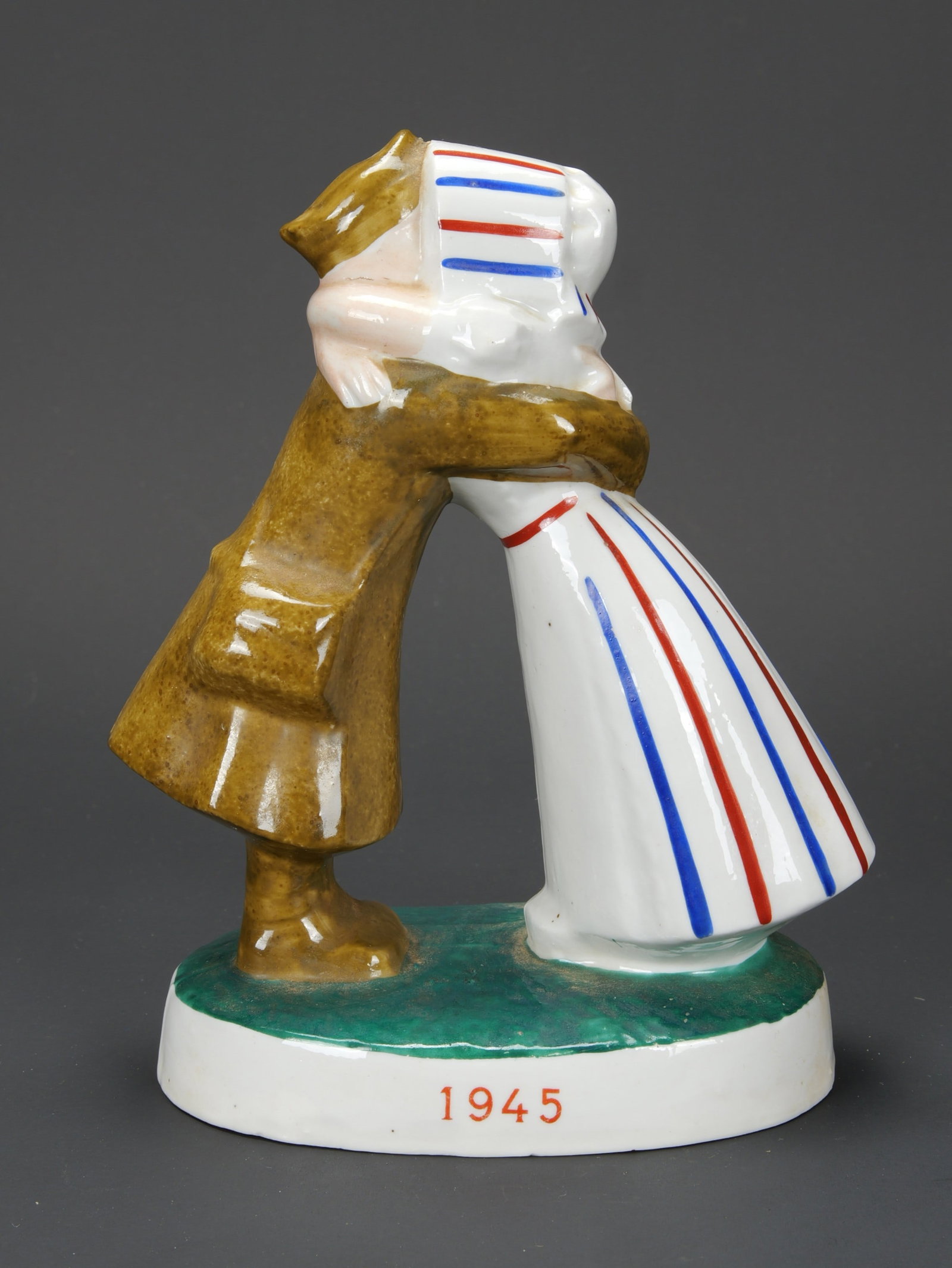 Retour du soldat francais. French statuette.: Retour du soldat francais. En porcelaine peinte. Femme portant une robe rayee bleu/blanc/rouge. Marquages Enfin 1945. Logo des entreprises presents sous le socle. Dimensions 19 x 15 cm. A noter une ce