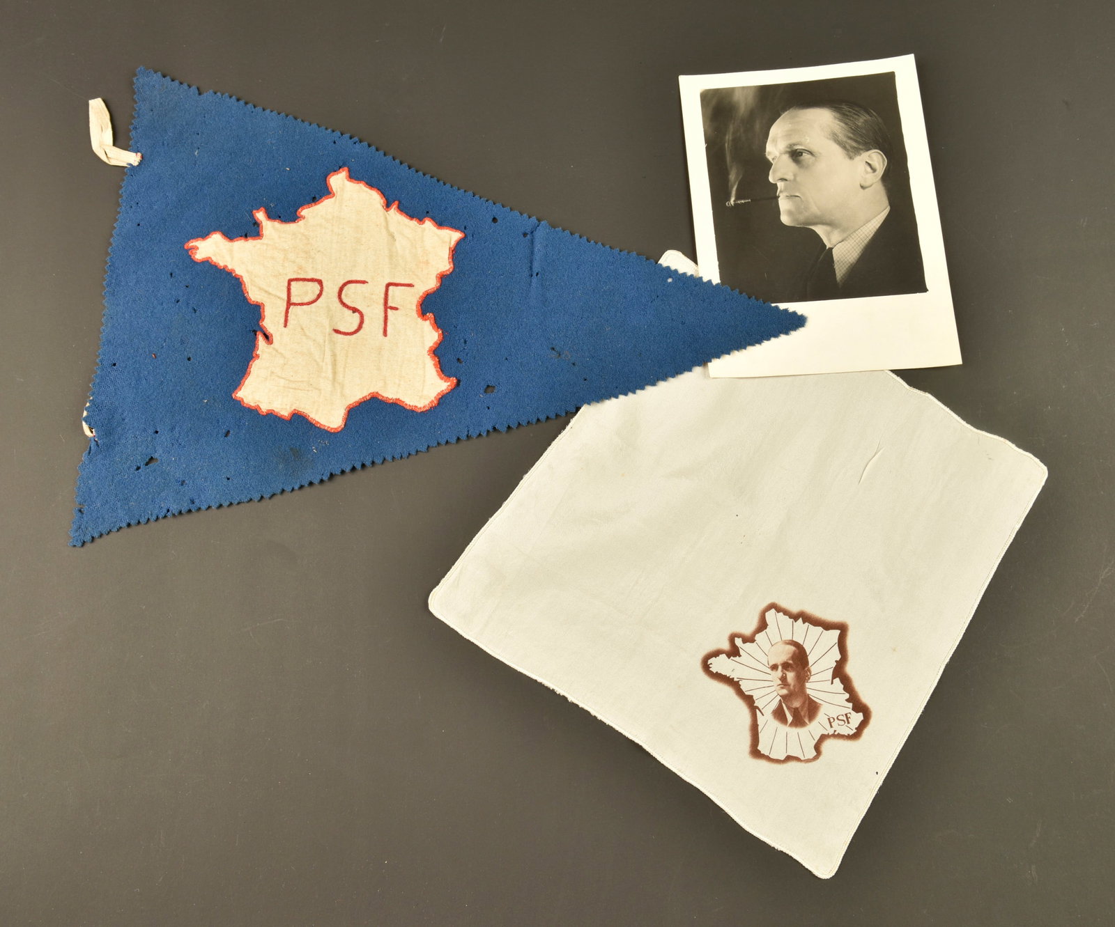 Ensemble PSF. PSF grouping.: Ensemble PSF. Comprenant un petit mouchoir en soie portant le visage du colonel de la Rocque rayonnant sur la France. Une photo portrait du colonel de la Rocque tamponnee au dos Photo Cine. Un fanion