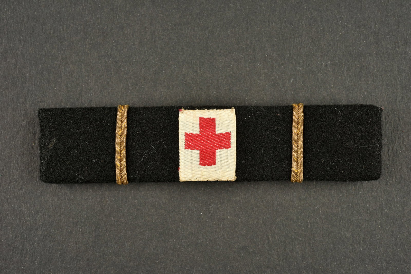 Barette d infirmiere major du SOL. Senior nurse armband of the SOL.: Barette d infirmiere major du SOL. Rare barrette d une infirmiere major du service d ordre legionnaire confectionnee en drap noir, portant au centre une croix rouge tissee sur fond blanc et de chaque