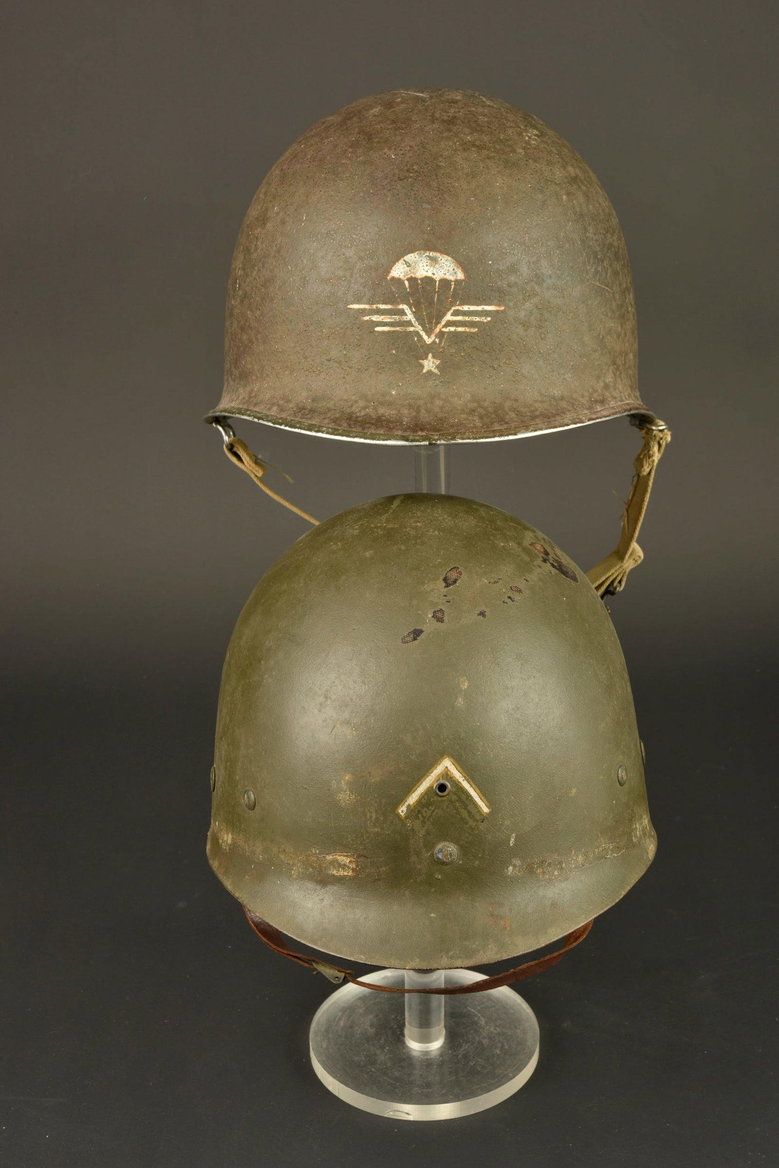 Casque USM1 RCP. US M1 helmet of the RCP. Camouflaged TAP jump jacket model 47/52.: Casque USM1 RCP. Casque lourd a pontets mobiles, jonc soude a l avant, jugulaire en toile OD, coque portant le numero de lot 934B. A l avant du casque se trouve l insigne parachutiste realise a la