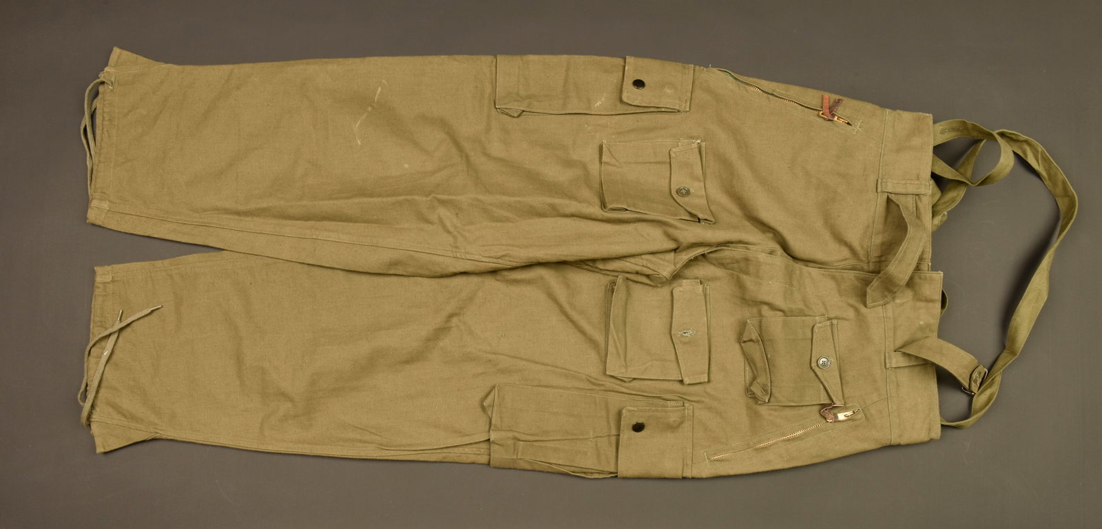 Pantalon de saut 47.51. Jump trousers model 47/51.: Pantalon de saut 47.51. Pantalon confectionne en toile kaki, deux poches laterales se fermant par des pressions bronzees, trois petites poches a rabat a l avant. Poches de hanches se fermant par deux 