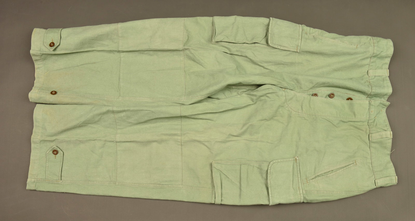 Pantalon TTA 47 Commando Marine. TTA 47 trousers of the Commando Marine.: Pantalon TTA 47 Commando Marine. Realise en coton dans une teinte specifique aux commandos marine, se fermant par trois boutons dissimules et possedant six passants. Pattes de serrage presentes au bas