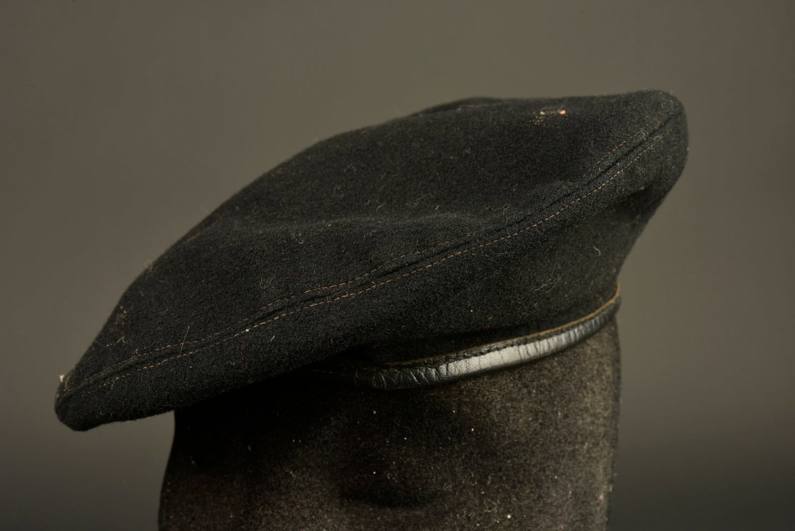Beret noir trois parties. Three-piece black beret.: Beret noir trois parties. Confectionne en drap noir en trois parties, doublure en coton marron clair portant le marquage d un tailleur a Paris, tampon du collectionneur. Pas d œillet d aeration,