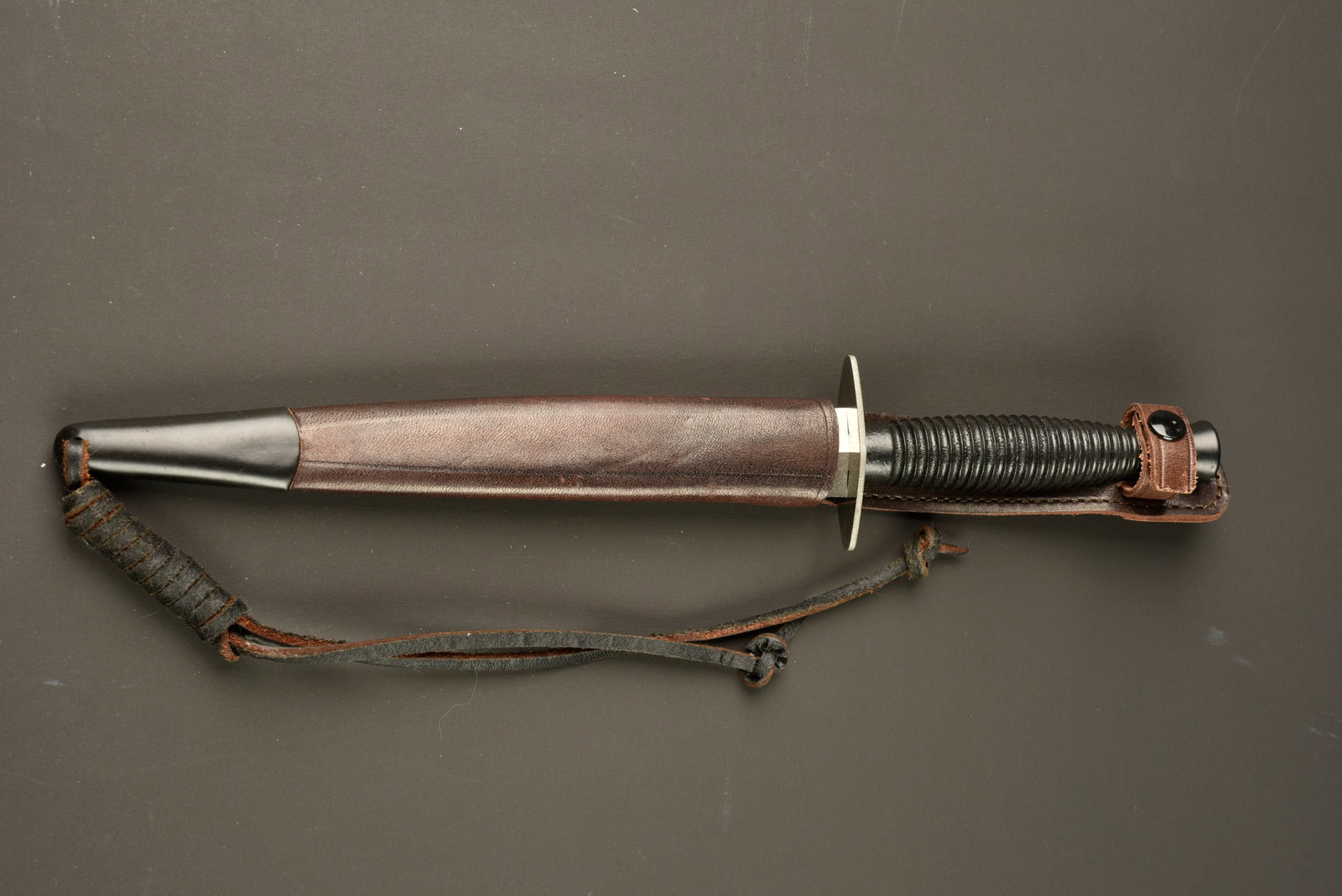 Dague Le commando a dents de scie. Le Commando dagger with sawback blade.: Dague Le commando a dents de scie. Poignard a dents de scie type Le Commando, poignee moulee en zamak recouverte d une peinture noire mate, comportant 26 cannelures. Garde d origine droite depourvue