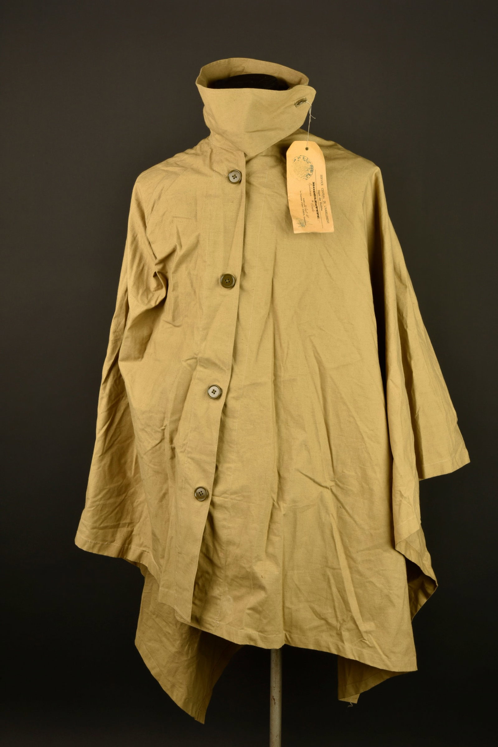 Poncho modele type. Poncho type model.: Poncho modele type. Poncho en toile impermeable kaki claire se fermant par quatre boutons portant le tampon du fabricant Magfa a Paris ainsi que l annee 1948. Est fixee d origine au poncho une etiquet