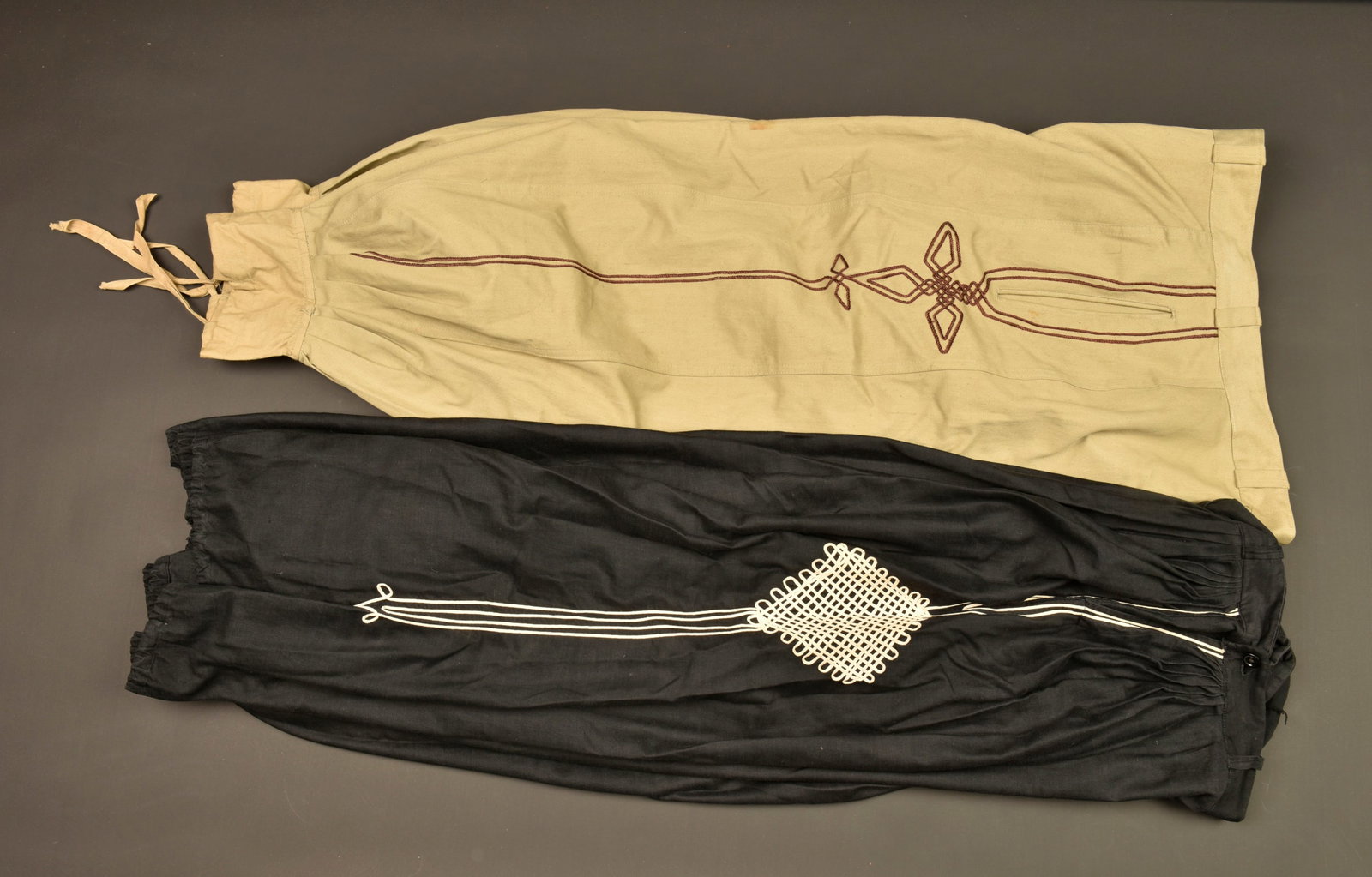 Ensemble de sarouels. Grouping of sarouel trousers.: Ensemble de sarouels. Comprenant un sarouel reglementaire troupe confectionne en toile de coton kaki, motifs a l oriental brodes au fil de coton marron. Marquage fabricant et taille 34 a l interieur a