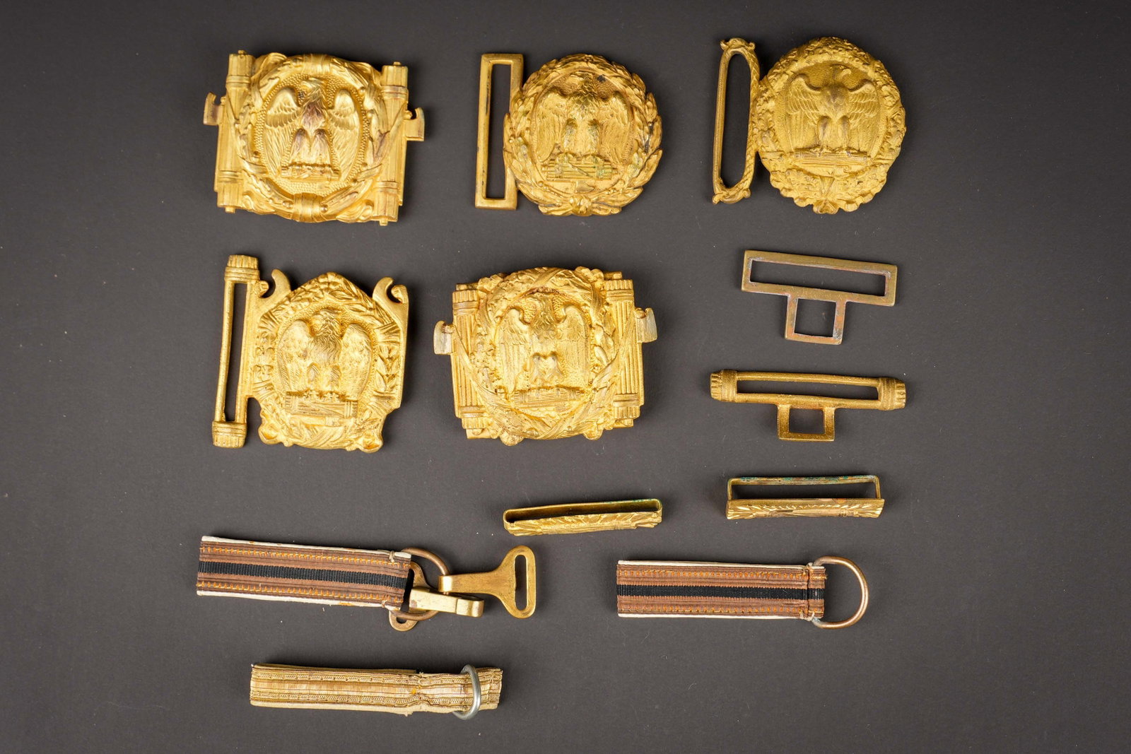 5 boucles du Parti National Fasciste. 5 buckles of the National Fascist Party.: Lot de 5 boucles du Parti National Fasciste, trois precoces de formes rondes et deux rectangulaires des annees de guerre. On y joint un ensemble de suspentes et attaches pour boucles de ceinturon. A n