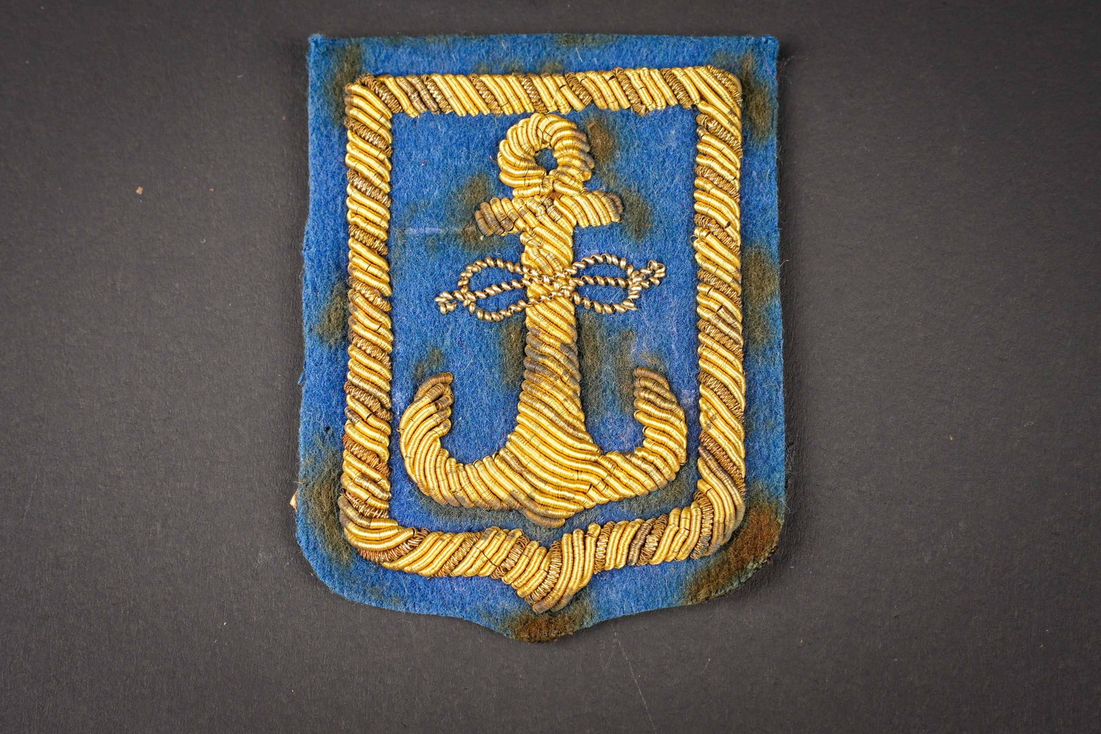 Insigne de la PAI. PAI insignia.: Insigne de la PAI. Modele pour officier de la police portuaire de la PAI. En cannetille or sur fond en drap bleu roi. Dos de la piece double en tissu coton noir. Etiquette marquee N 165 PAI Polizia Po