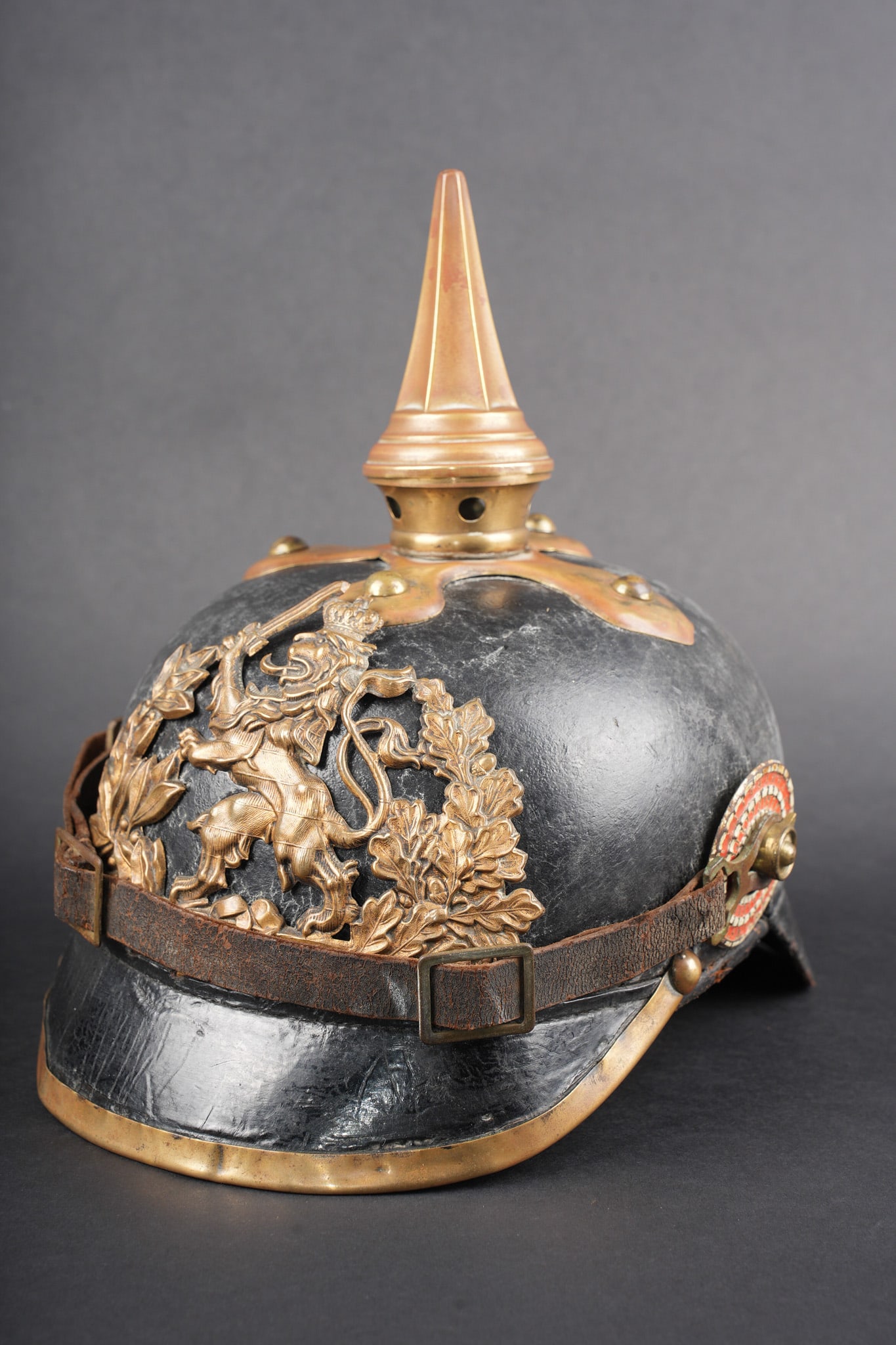 Casque a pointe M1895 Hessois. M1895 Hessian spiked helmet.: Casque a pointe M1895 Hessois. Bombe en cuir noirci, usure, non repercee. Marquage fabricant a l interieur a dechiffrer. Toutes garnitures laiton, plaque au lion hessois, pontets soudes d origine. Poi