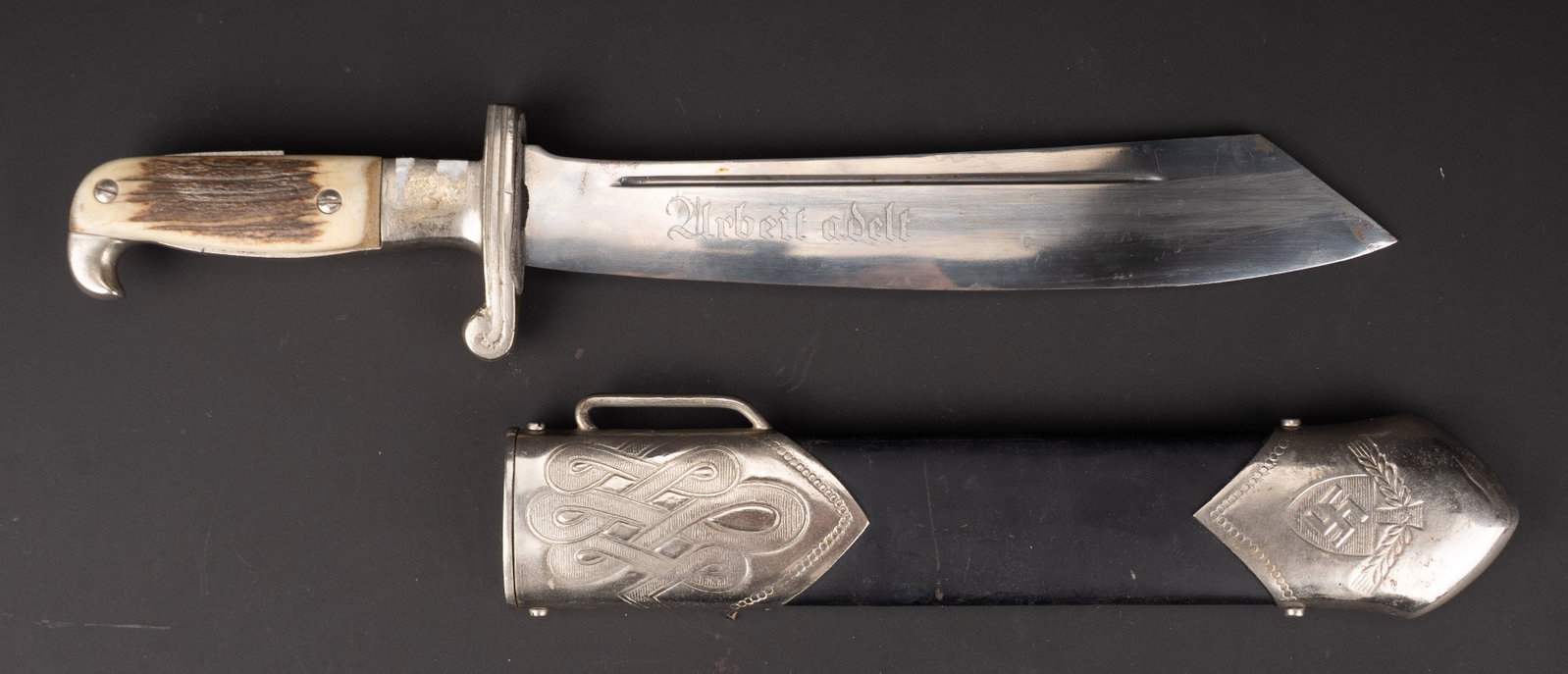 Reproduction de dague RAD. Reproduction RAD dagger.: Reproduction de dague RAD. Garnitures metalliques, un manque visible au niveau de la tranche de la poignee. Plaquette en imitation corne. Fourreau en metal, peinture noire a 70%. Lame marquee RZM