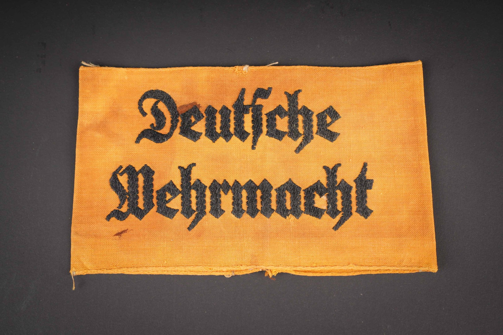 Brassard Deutsche Wehrmacht. German Wehrmacht armband.: Brassard Deutsche Wehrmacht. En tissu coton jaune, fortement sale, reste de tampon illisible. Marquages Deutsche Wehrmacht brode en fils noir. A noter une certaine usure et patine de la piece, ainsi